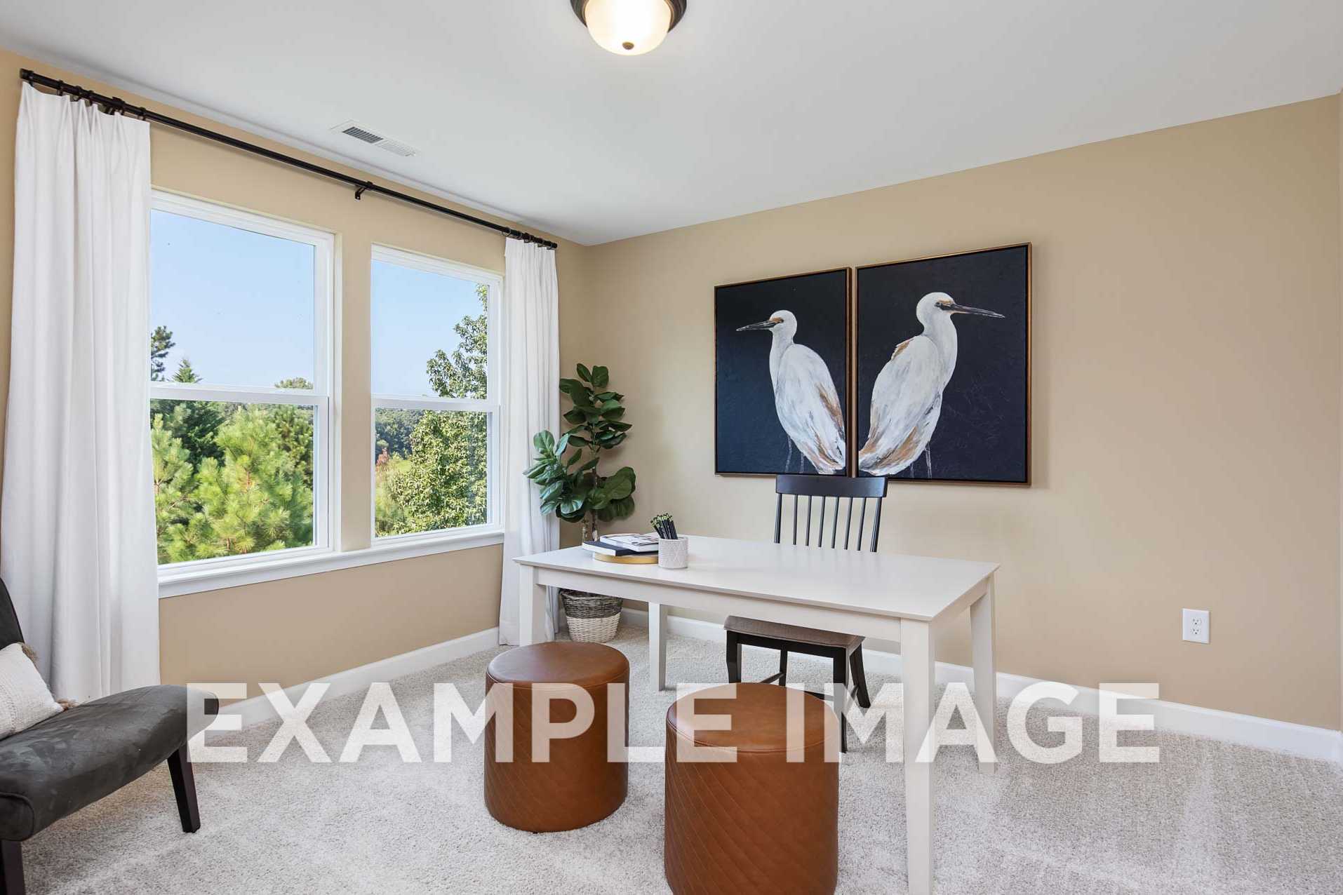 Spacious upper-floor home office in The Willow F with large windows, egret wall art, wooden desk, and leather armchair