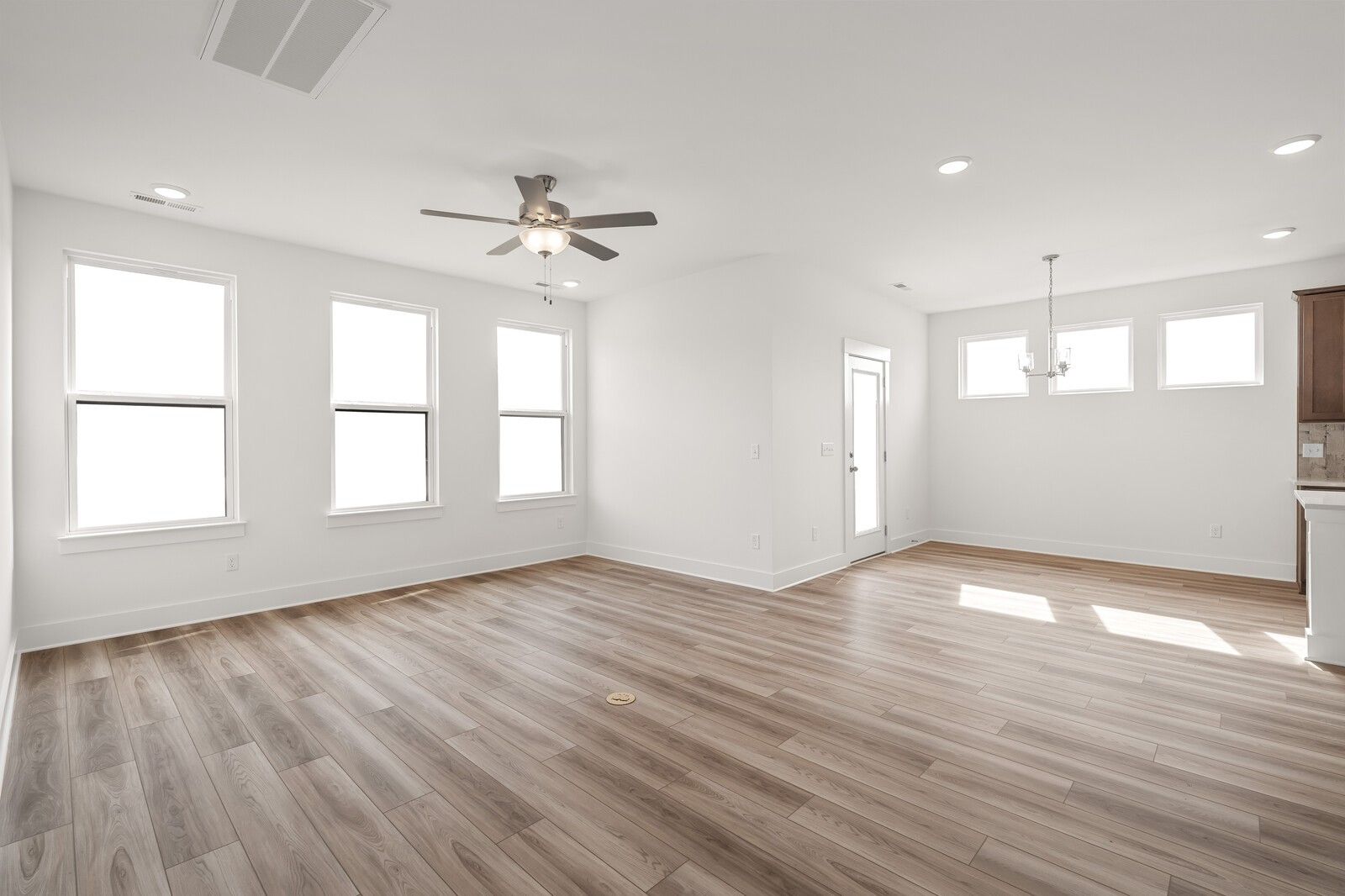 Bright open living room with large windows, ceiling fan, chandelier, and hardwood floors in Davidson Homes The Ash C, Mt. Juliet, TN
