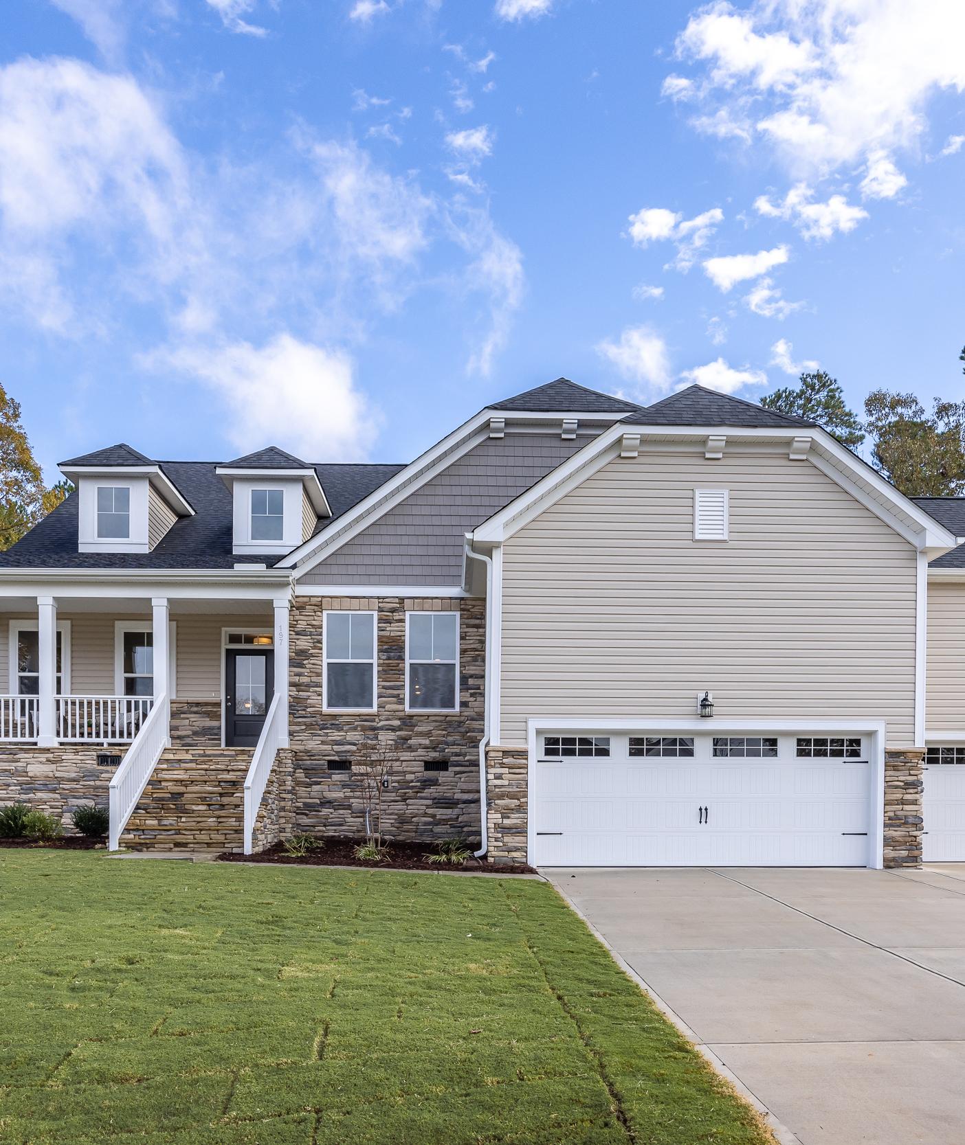 Single-family home exterior at Tobacco Road in Angier, NC built by Davidson Homes with stone facade and three-car garage.