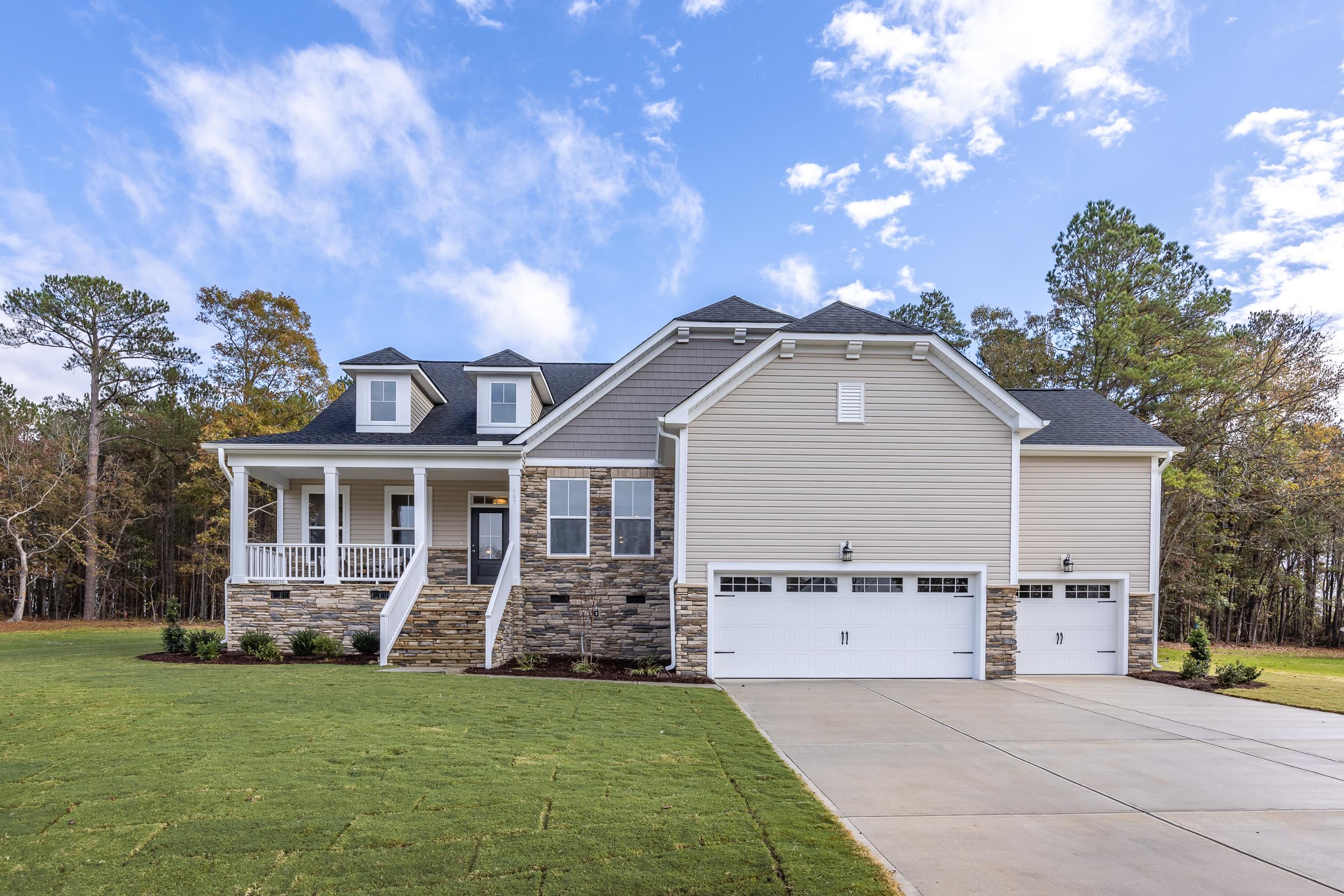 Single-family home exterior at Tobacco Road in Angier, NC built by Davidson Homes with stone facade and three-car garage.