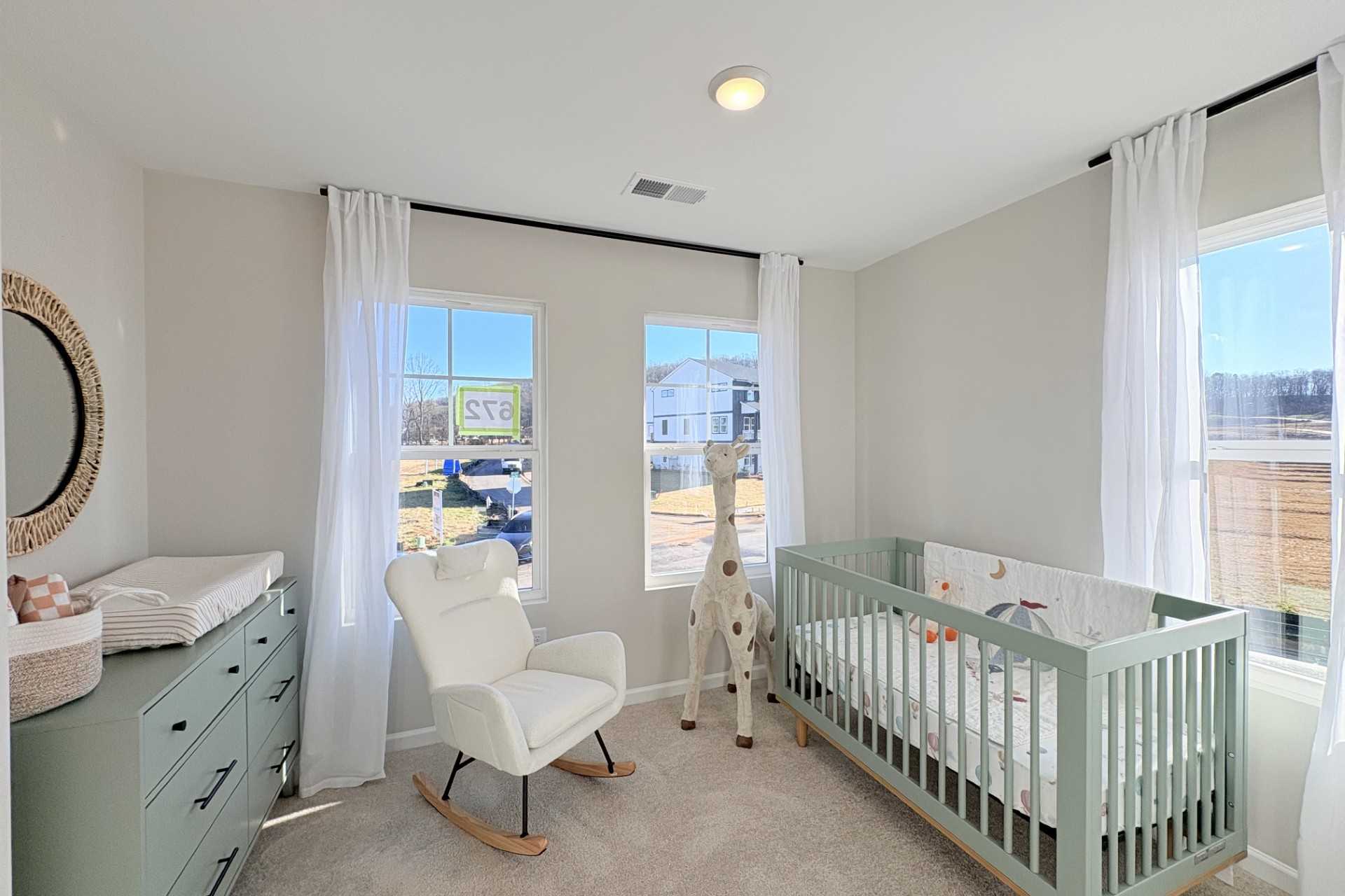Cozy nursery in Hemingway Cumming GA with green crib, white rocking chair, giraffe toy, and sheer-curtained windows by Davidson Homes