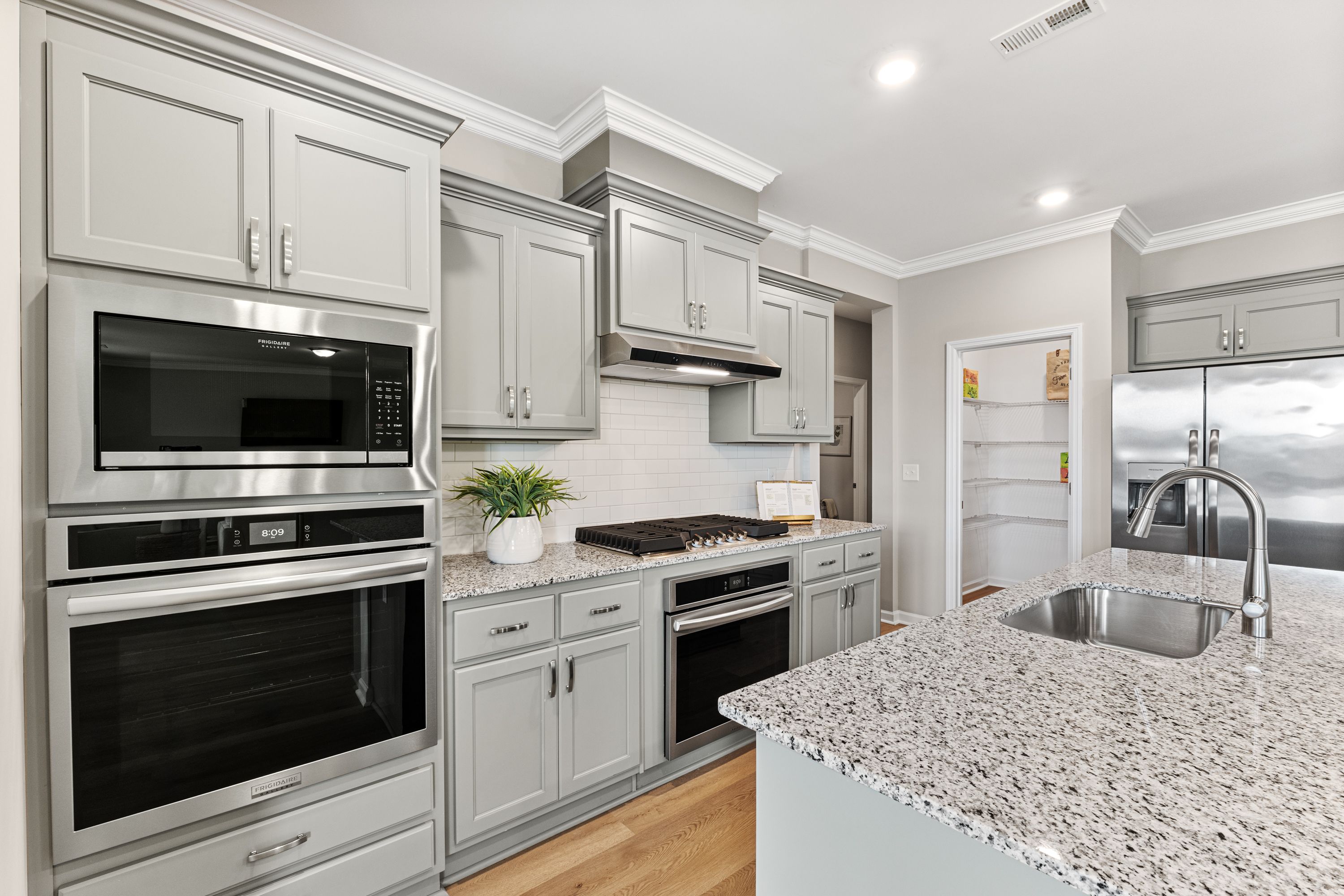 Spacious modern kitchen at Anderson Farm in Athens Alabama with gray shaker cabinets stainless steel double oven and granite island sink