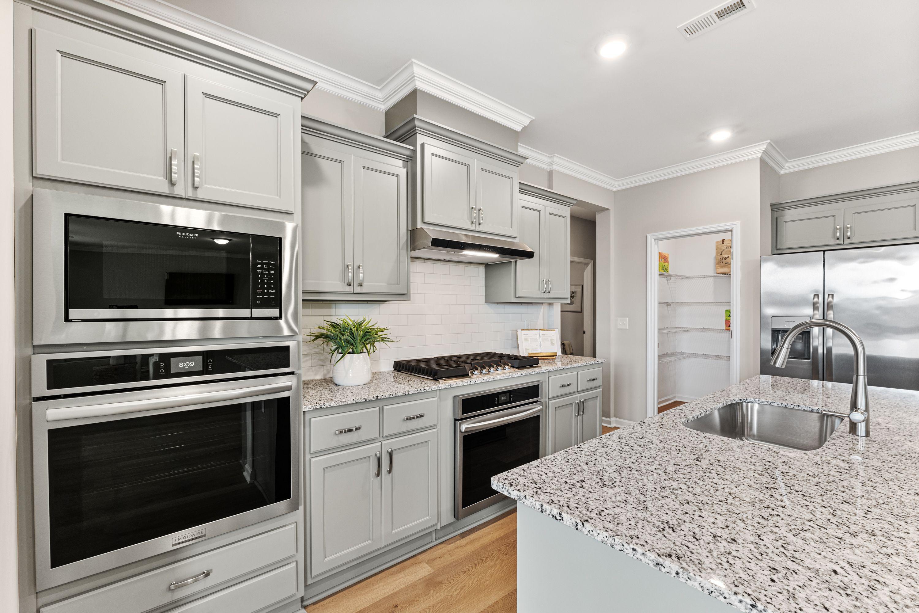 Spacious modern kitchen at Anderson Farm in Athens Alabama with gray shaker cabinets stainless steel double oven and granite island sink