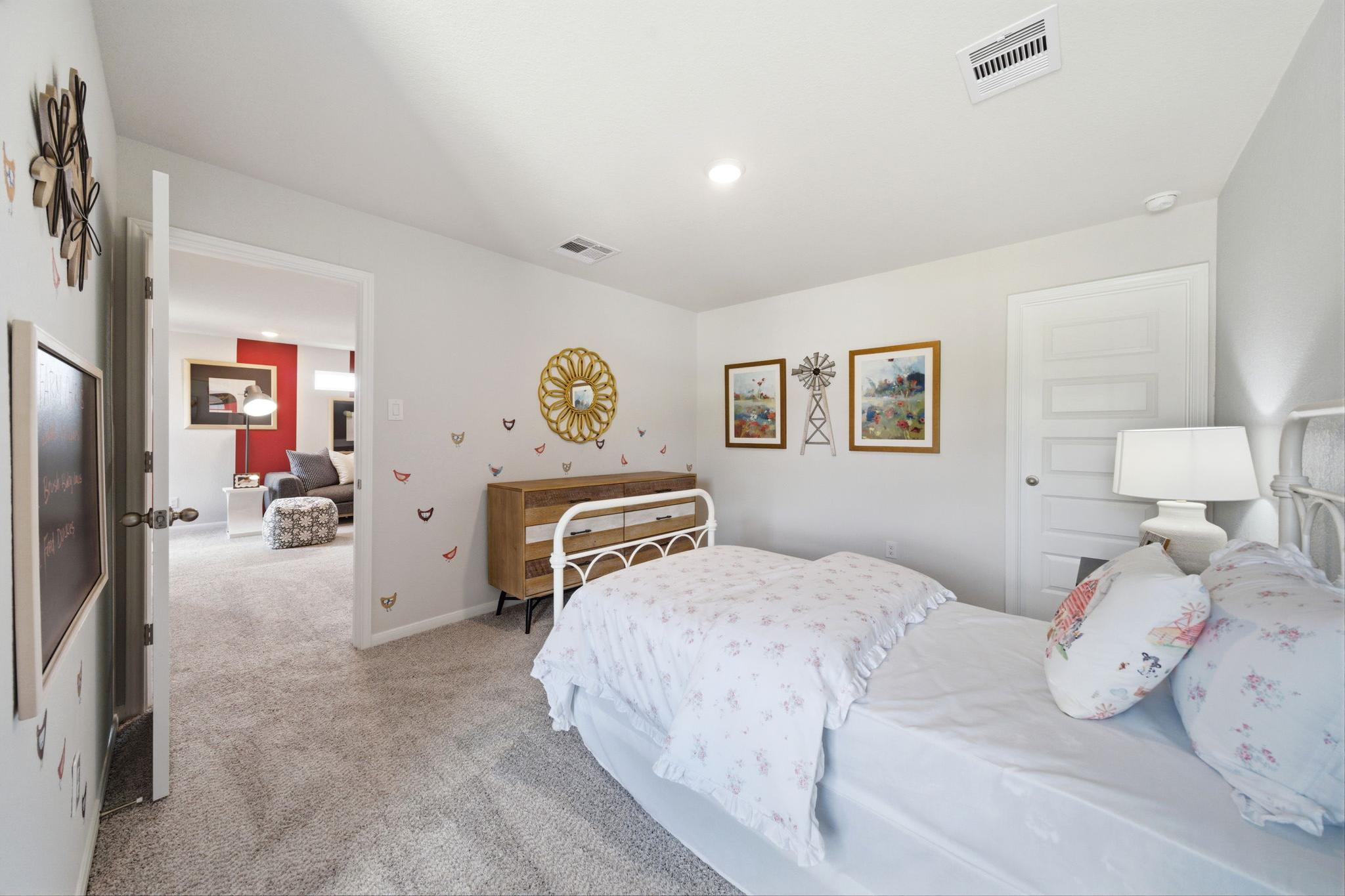 Cozy girl's bedroom at Liberty Estates in Cleveland, Texas with twin bed, pink floral bedding, butterfly decals and windmill art