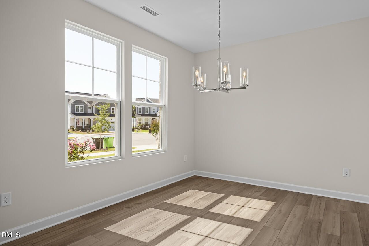 Bright dining room with vinyl plank flooring, modern chandelier, and large windows in Davidson Homes The Willow C, Zebulon NC