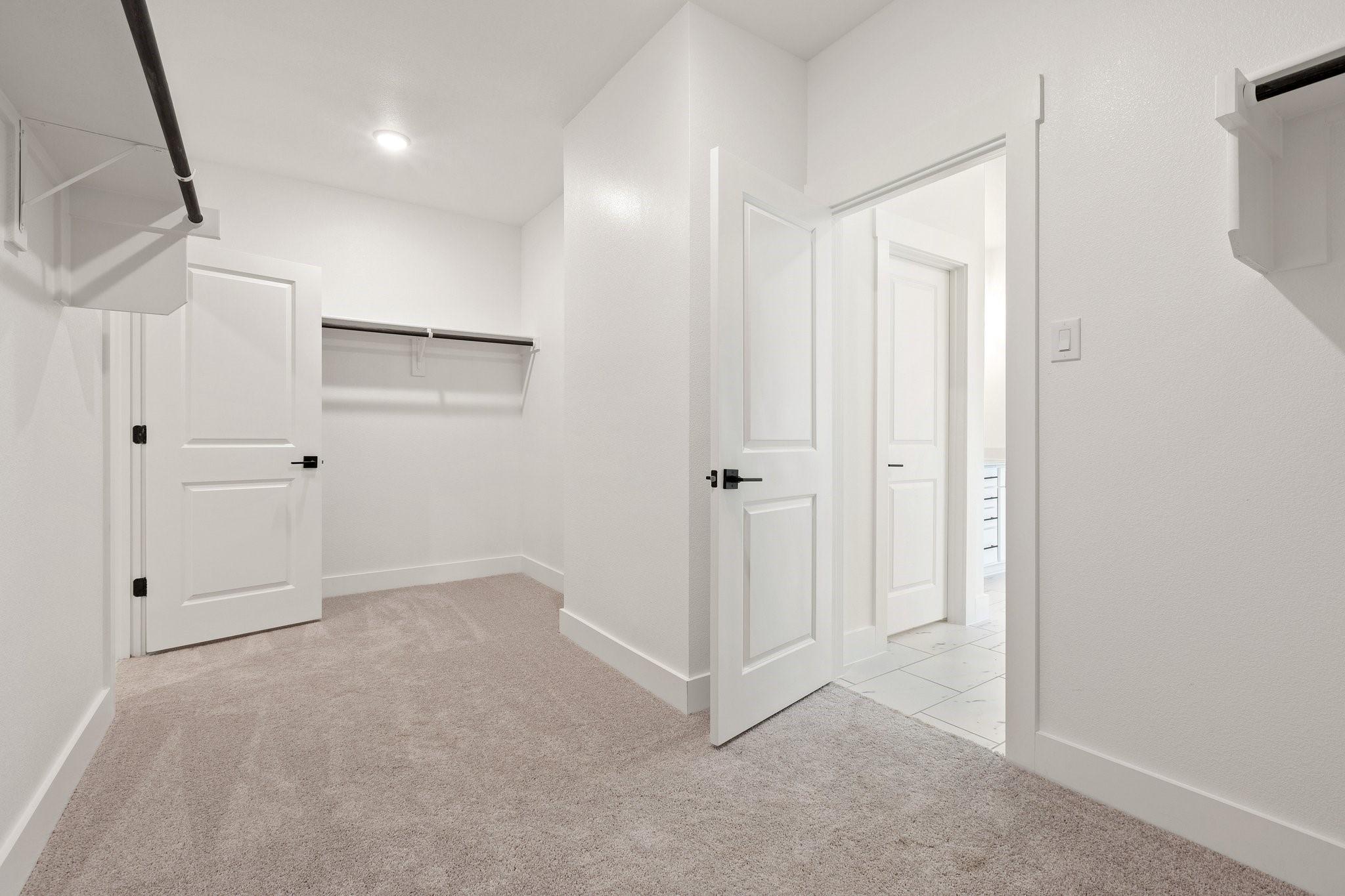 Walk-in closet with carpeted flooring and shelving in The Rockford C floor plan at Waverly Estates, Josephine, Texas.