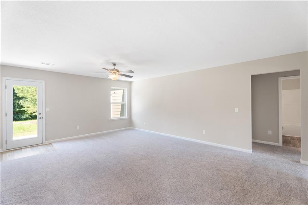 Spacious living room with carpet, ceiling fan, and backyard access in The Washington floor plan, Summer Vineyard, AL.