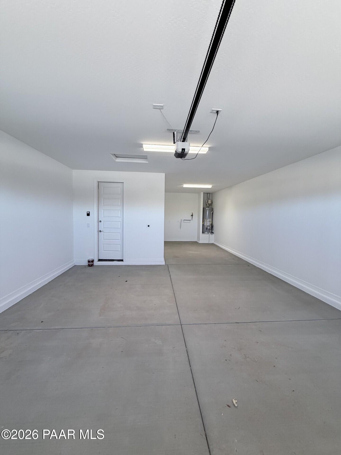 Spacious 3-car garage with white walls and water heater in The Frontier A home at North Ridge, Prescott Valley, Arizona.