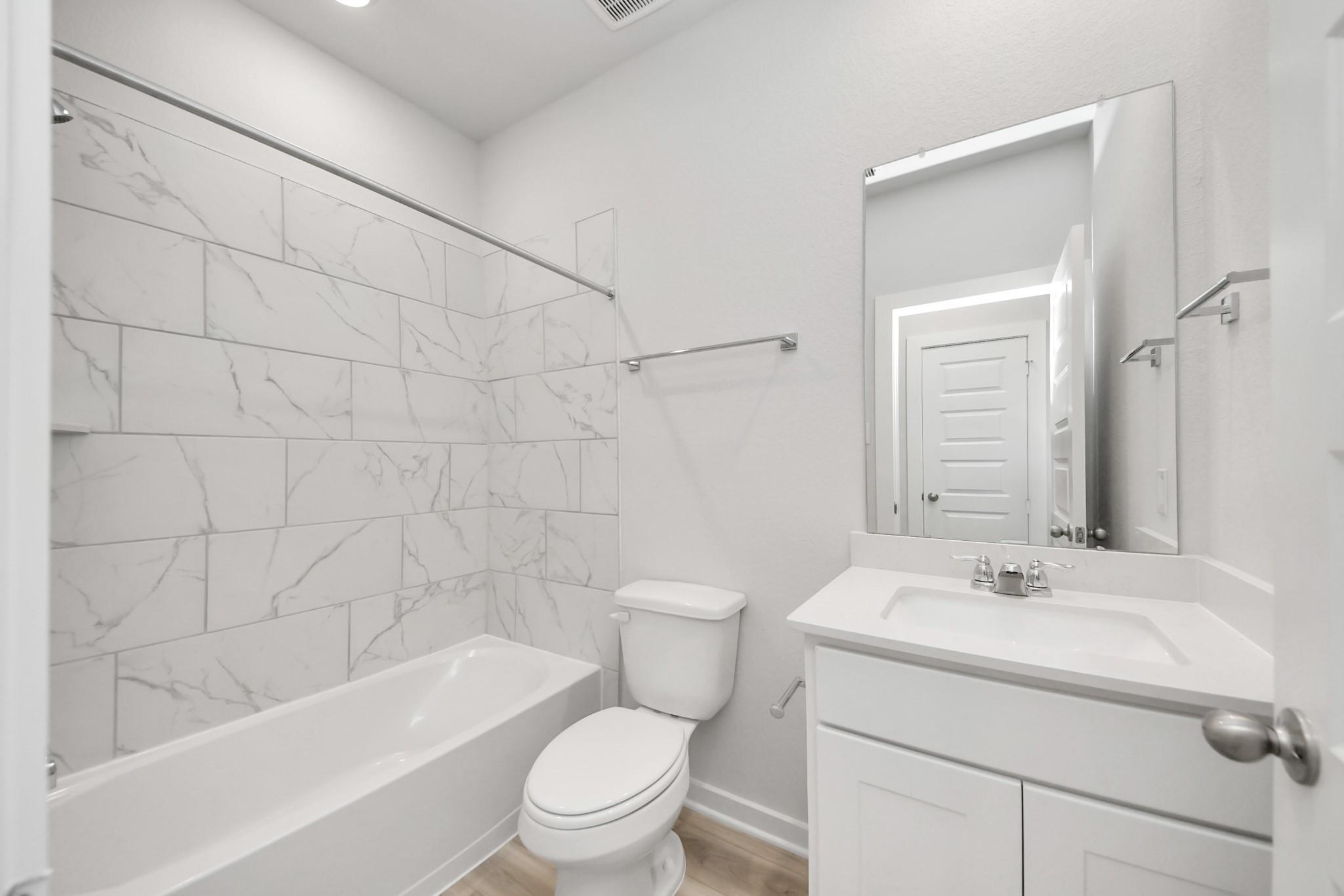 Modern bathroom with white marble-style tile shower surround in The Sabine F plan at Liberty Estates, Cleveland, Texas.