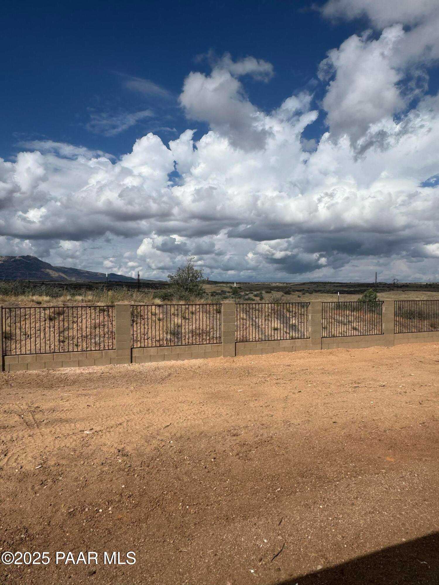 Scenic desert backyard with stucco fence, distant mountains, and blue sky in Davidson Homes The Monarch E, Westwood, Prescott, Arizona