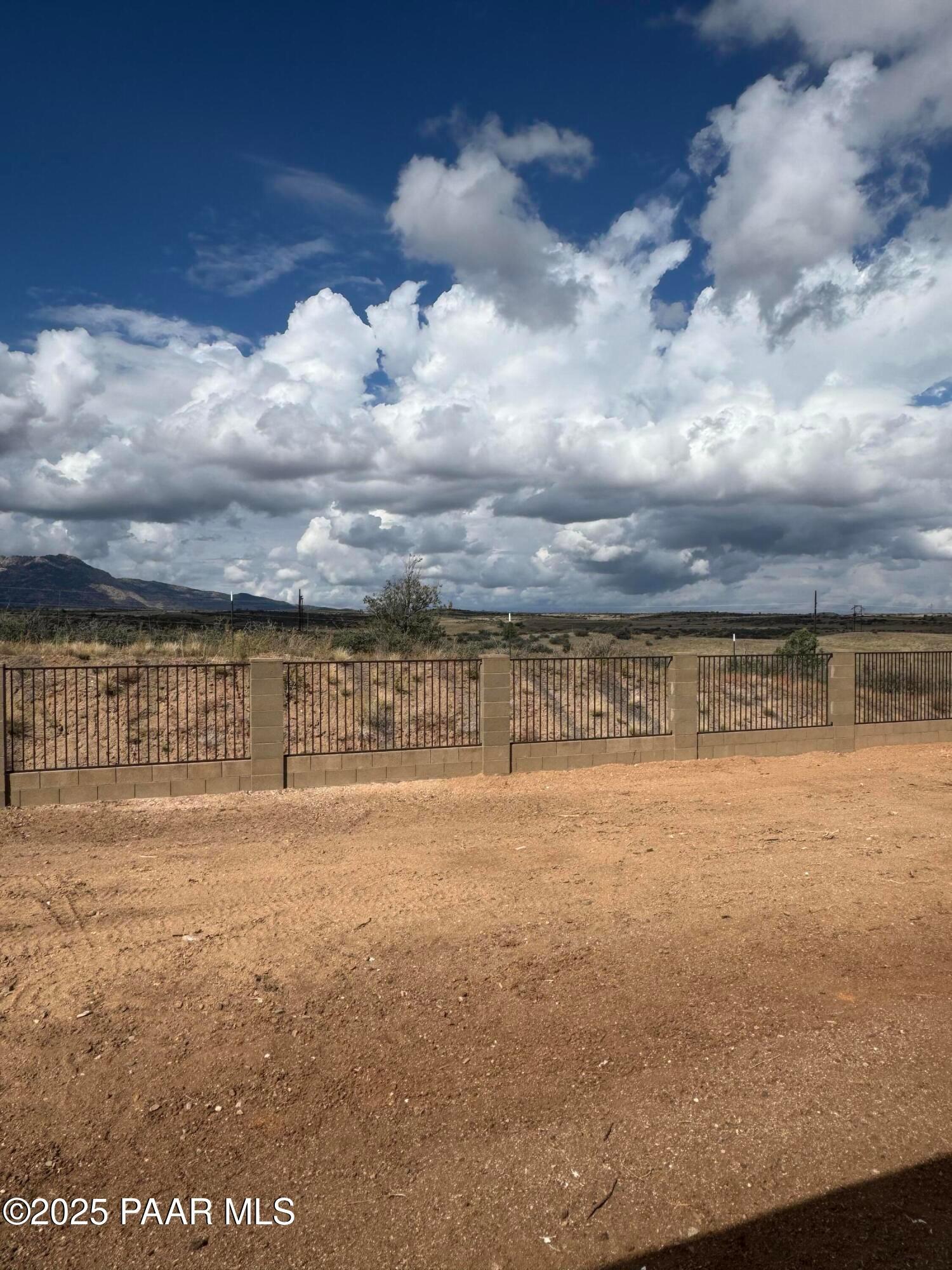 Scenic desert backyard with stucco fence, distant mountains, and blue sky in Davidson Homes The Monarch E, Westwood, Prescott, Arizona