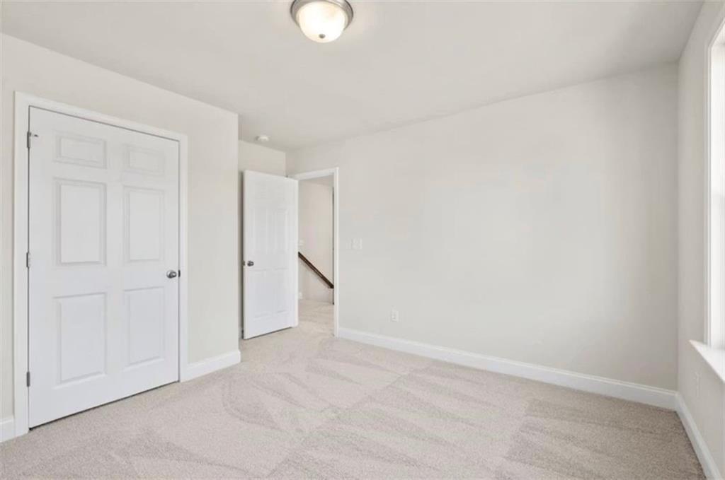 Bright, neutral-toned bedroom with plush carpet in The Ash C floor plan at Wehunt Meadows in Hoschton, Georgia.