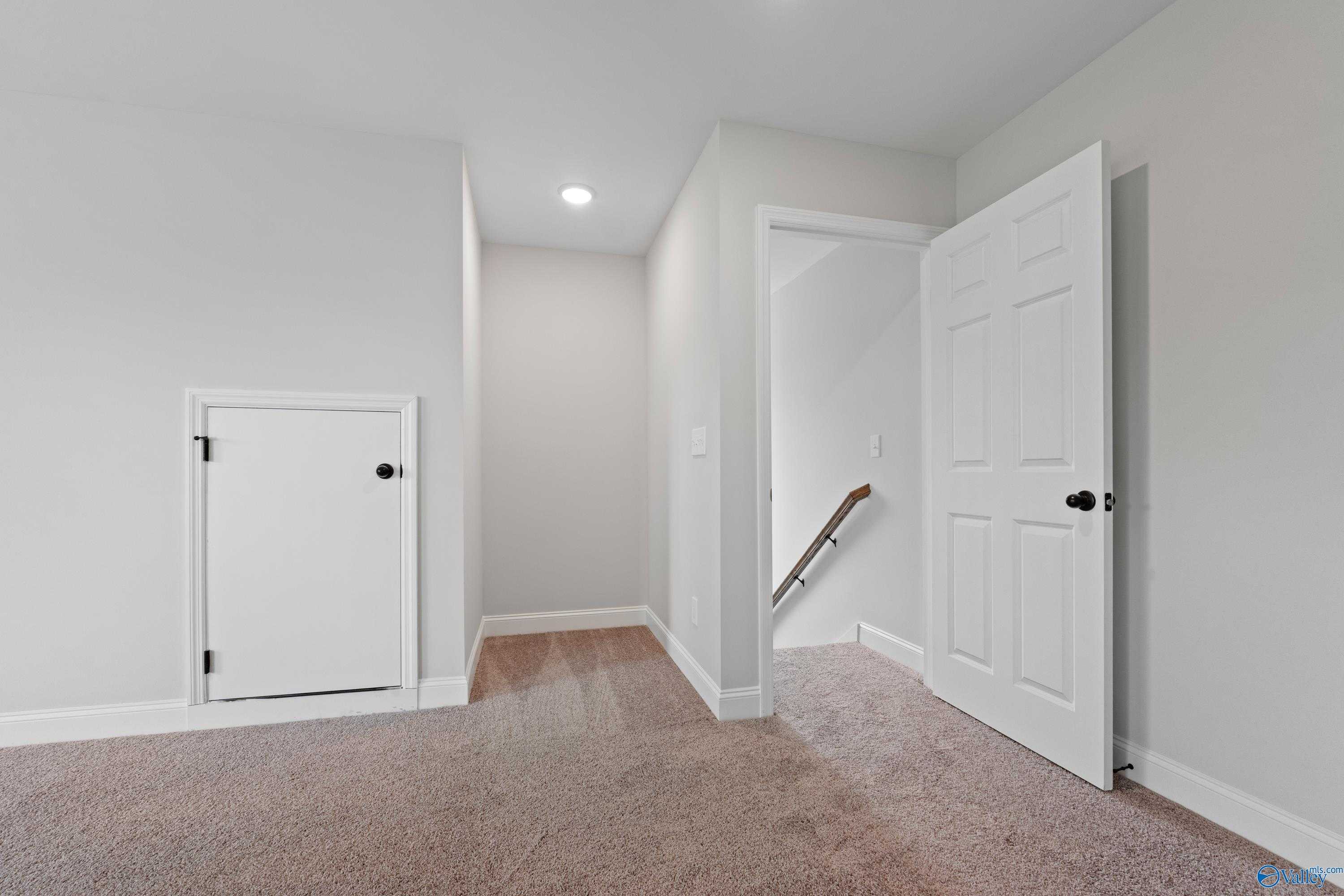 Bonus room hallway featuring stairs with wood railing, white doors, neutral walls, and carpeted floors in The Kirkland with Bonus, Harvest, AL