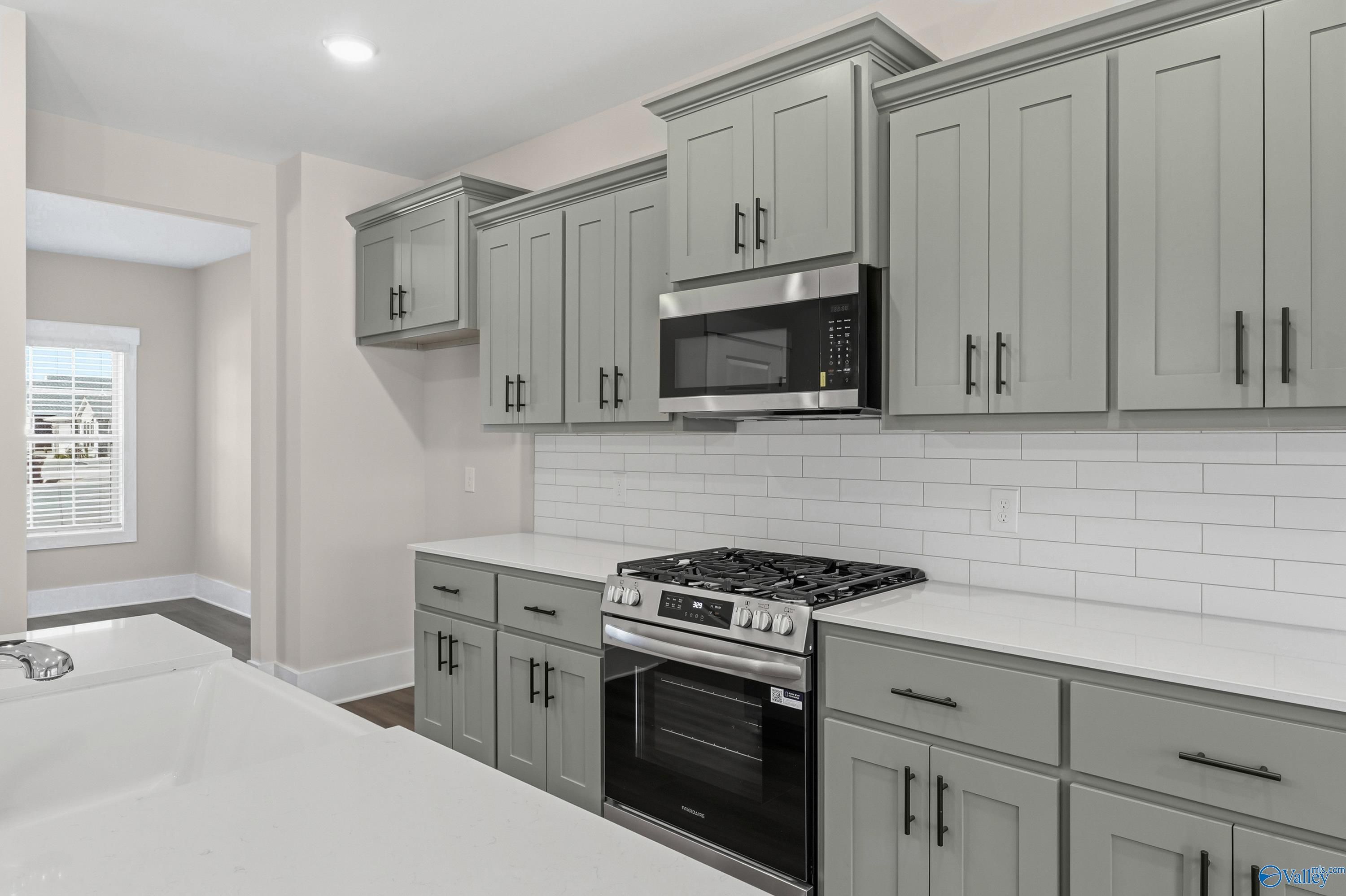 Modern kitchen with gray shaker cabinets, stainless steel appliances, subway tile backsplash in The Shelby A, Athens AL