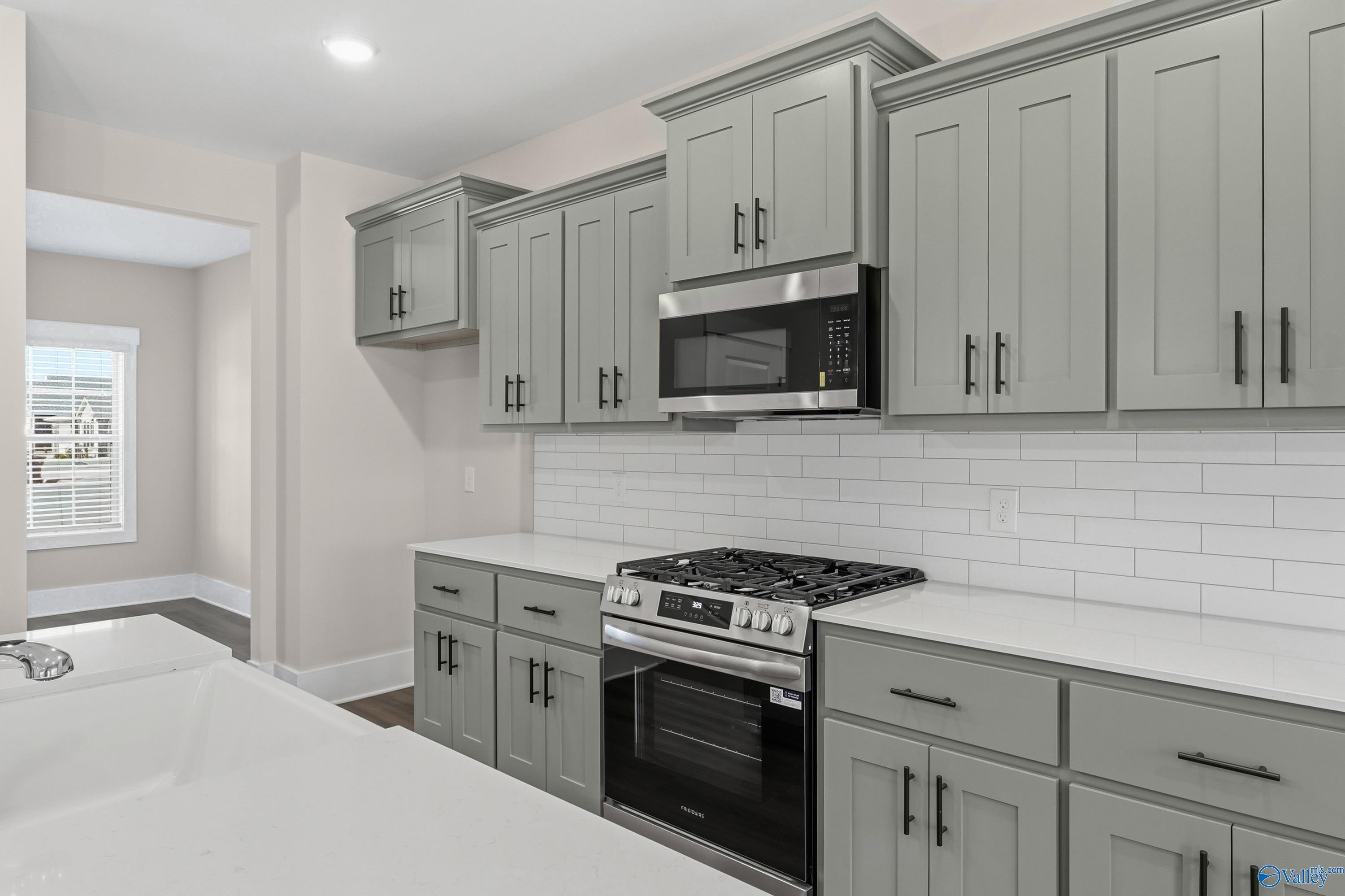 Modern kitchen with gray shaker cabinets, stainless appliances, subway tile backsplash in Davidson Homes The Shelby A, Athens, AL