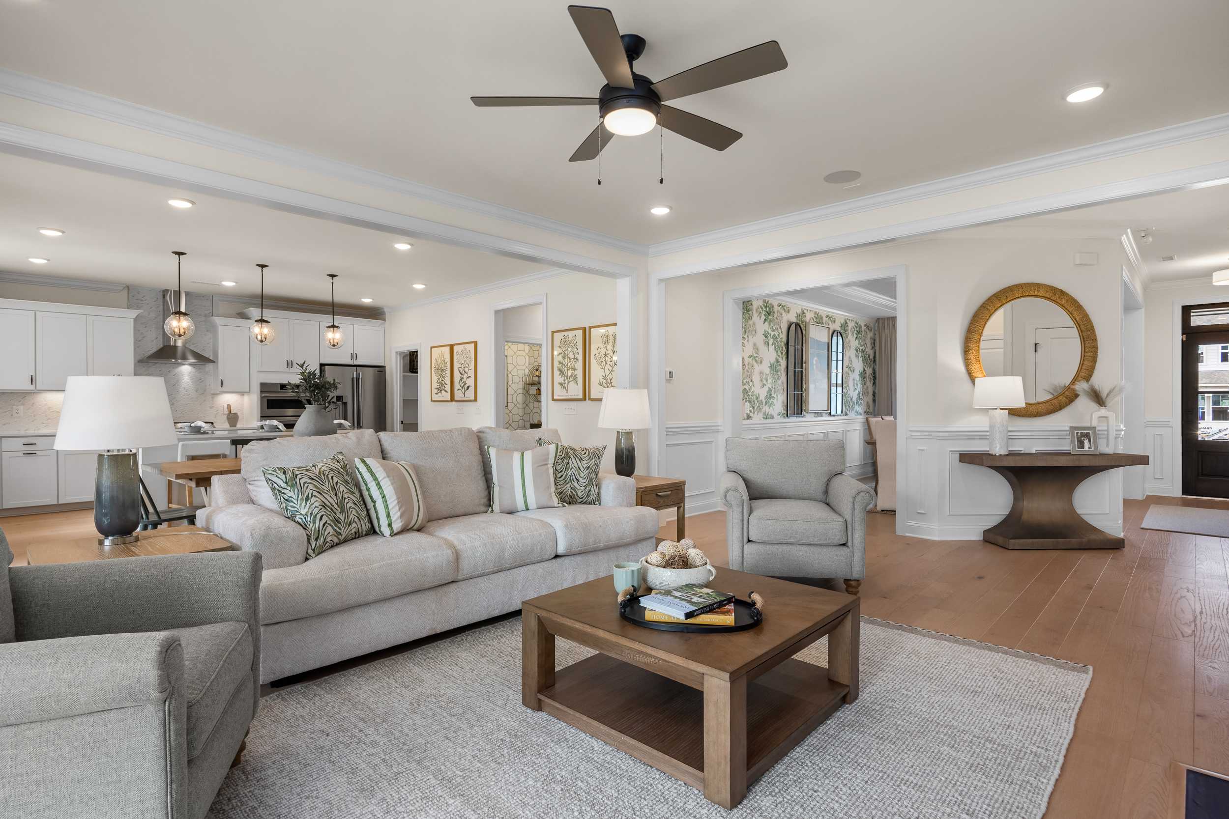 Open-concept living room at Laneridge Estates in Raleigh NC with beige sofas, wooden coffee table, and ceiling fan