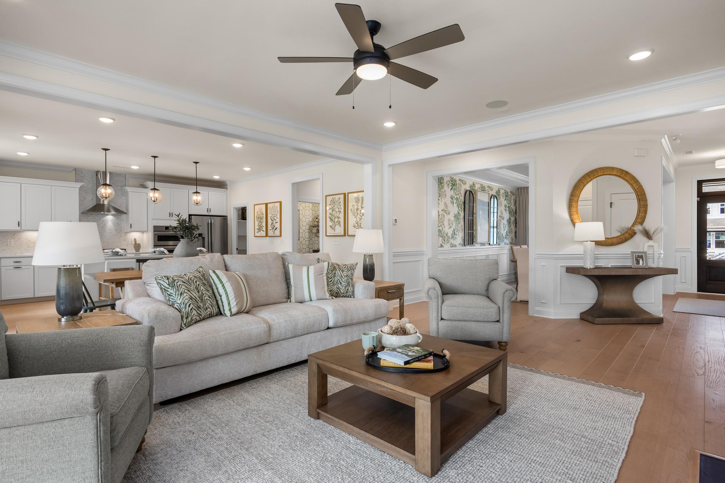 Open-concept living room at Laneridge Estates in Raleigh NC with beige sofas, wooden coffee table, and ceiling fan