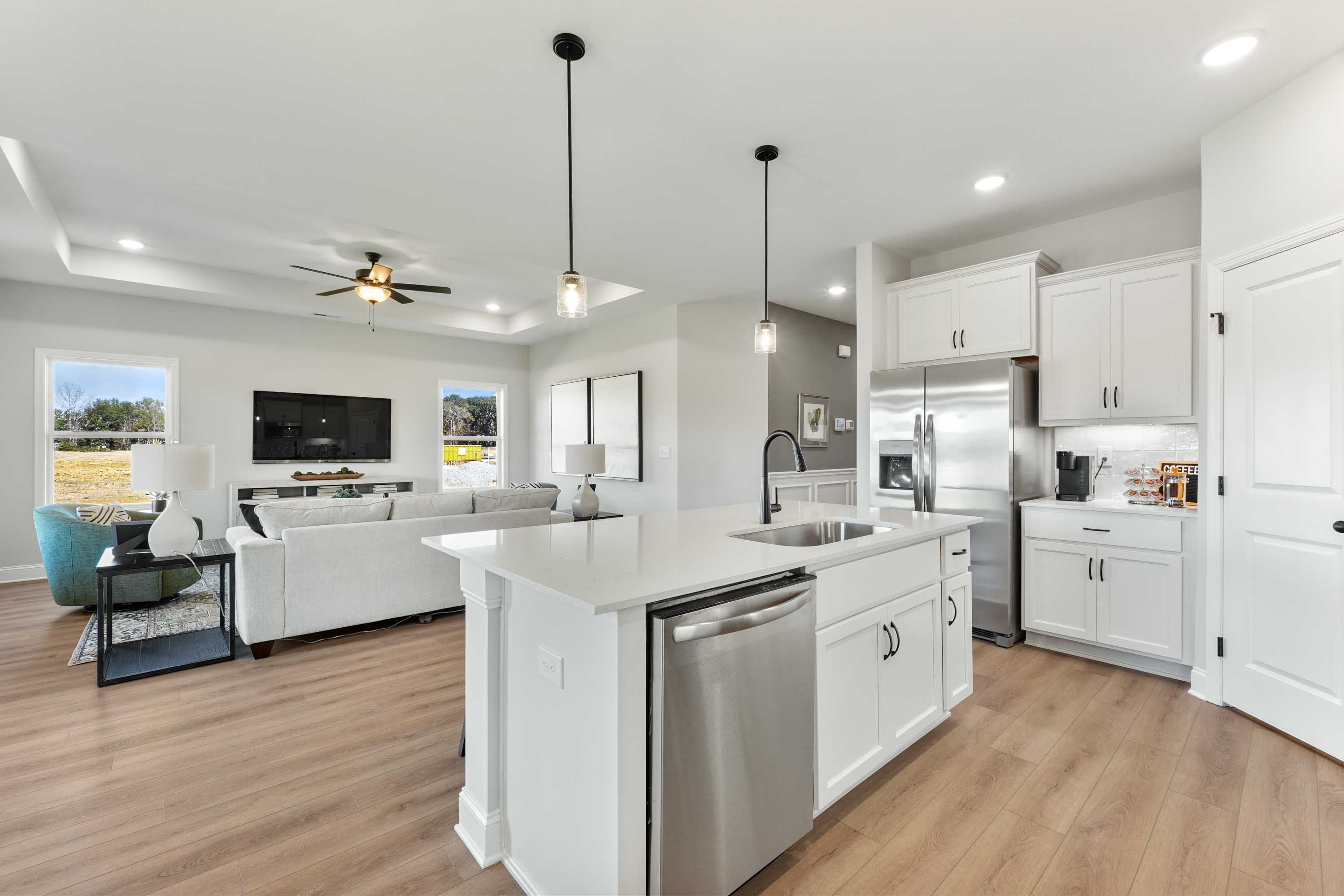 Open-concept kitchen and living room in Ramsay Cove, Owens Cross Roads AL featuring white island, hardwood floors, large windows
