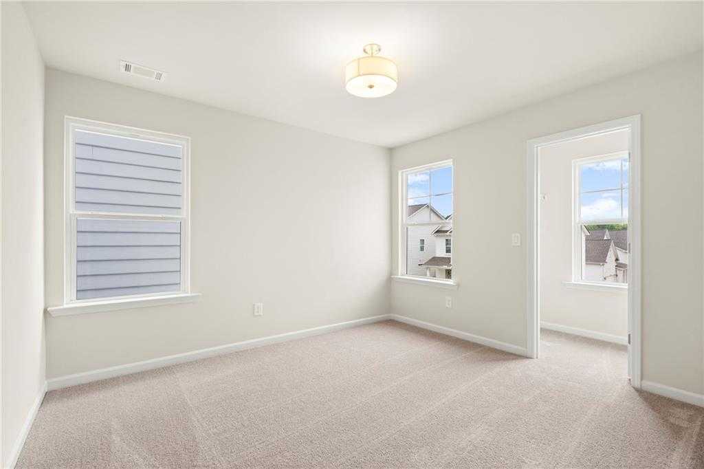 Bright secondary bedroom with beige carpet, large windows, and neutral walls in Davidson Homes The Cary A, Kennesaw, Georgia