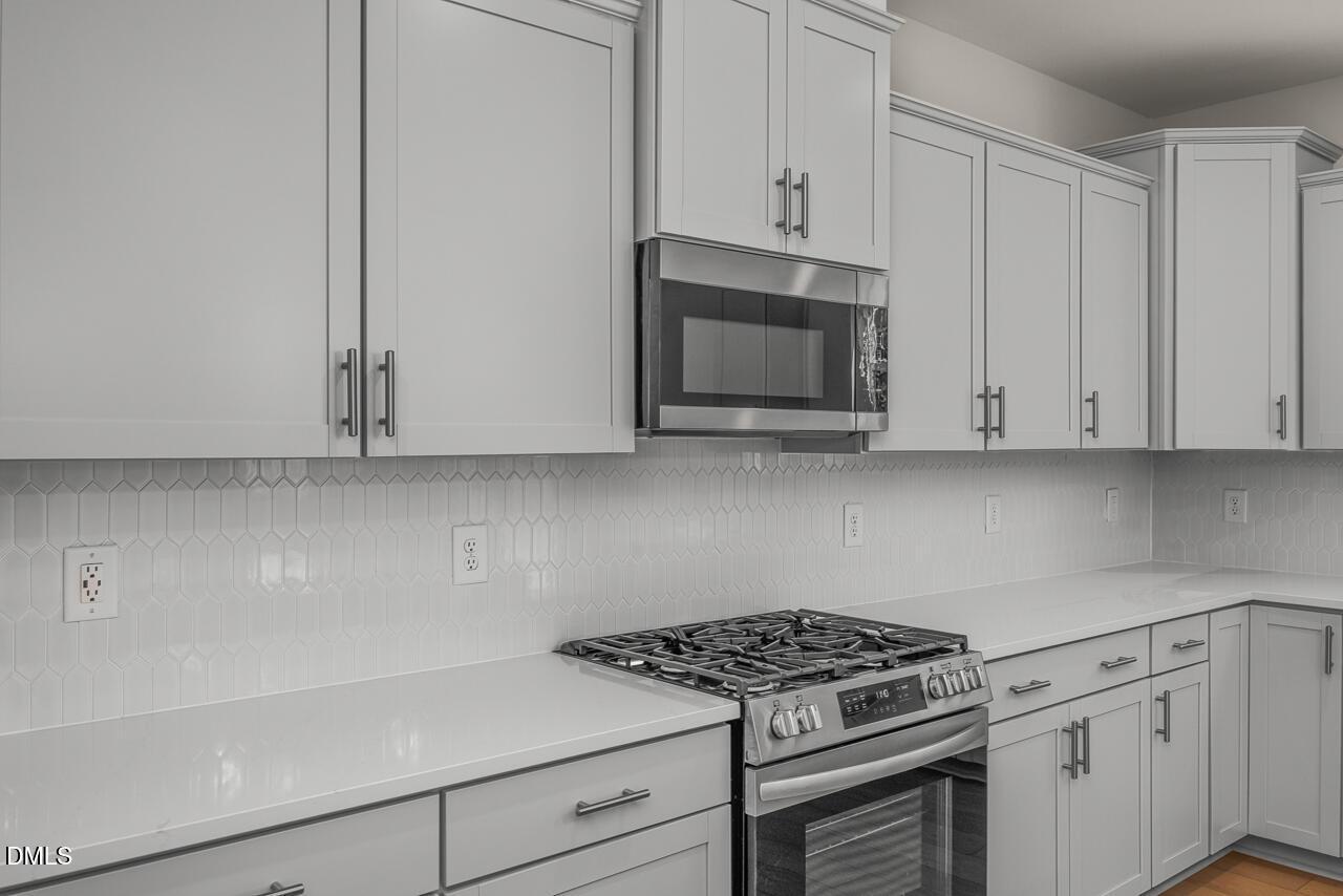Modern kitchen with gray shaker cabinets, hexagon tile backsplash, and gas range in Davidson Homes Hickory II C, Aberdeen NC