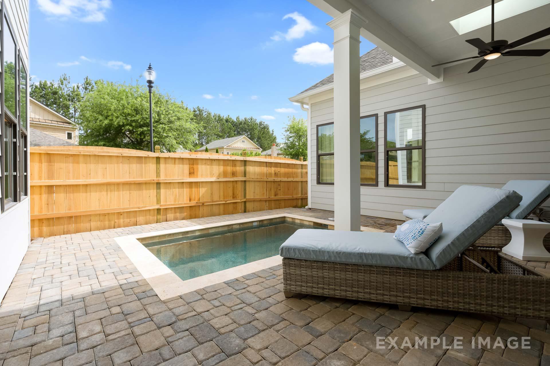 Spacious backyard pool patio in The Seaside C home design with lounge chairs, paver deck, and wooden fence, Davidson Homes Woodstock GA