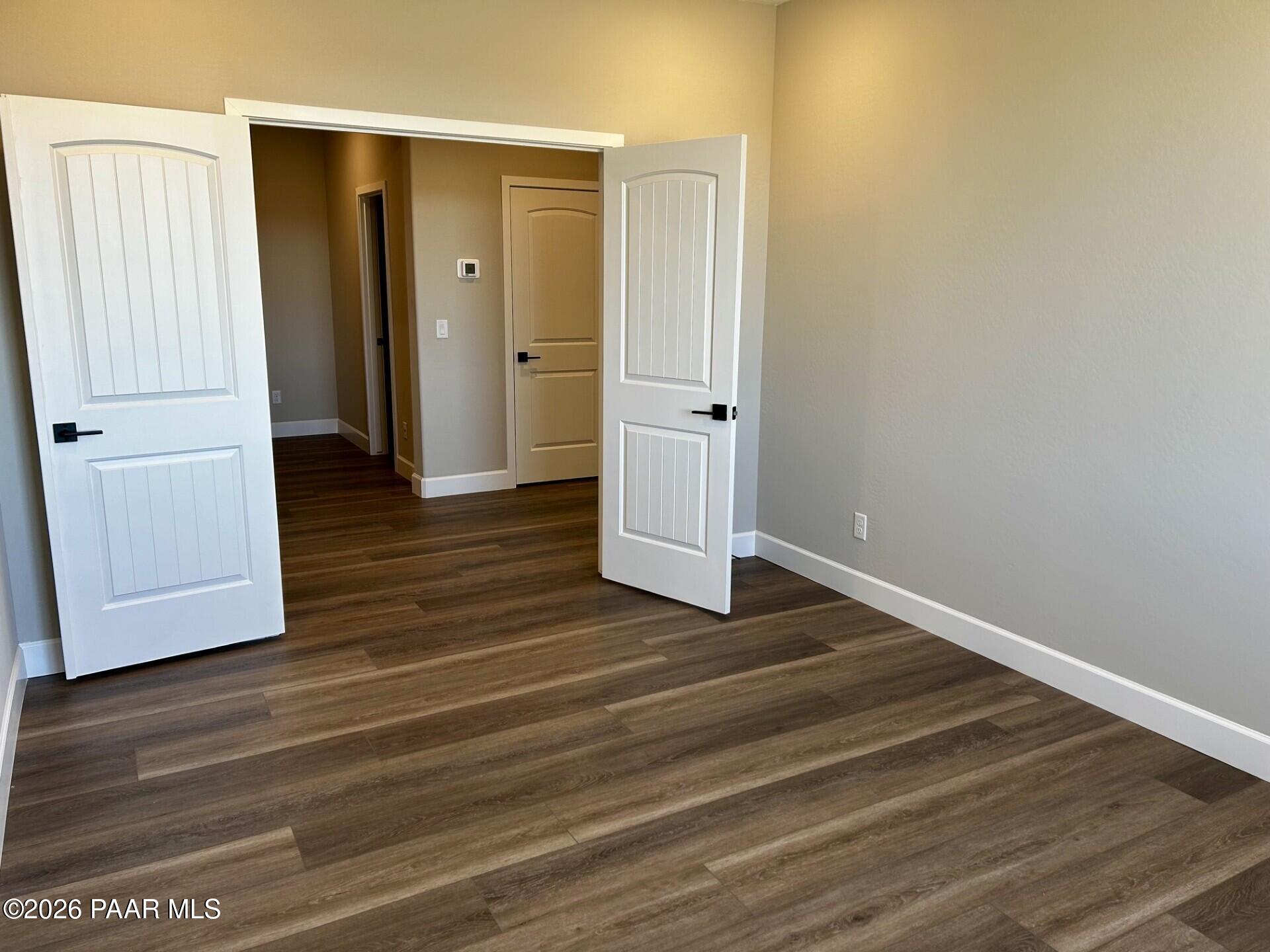 Spacious bedroom with wood-look flooring and double doors in The Harmony C floor plan at North Ridge, Prescott Valley.