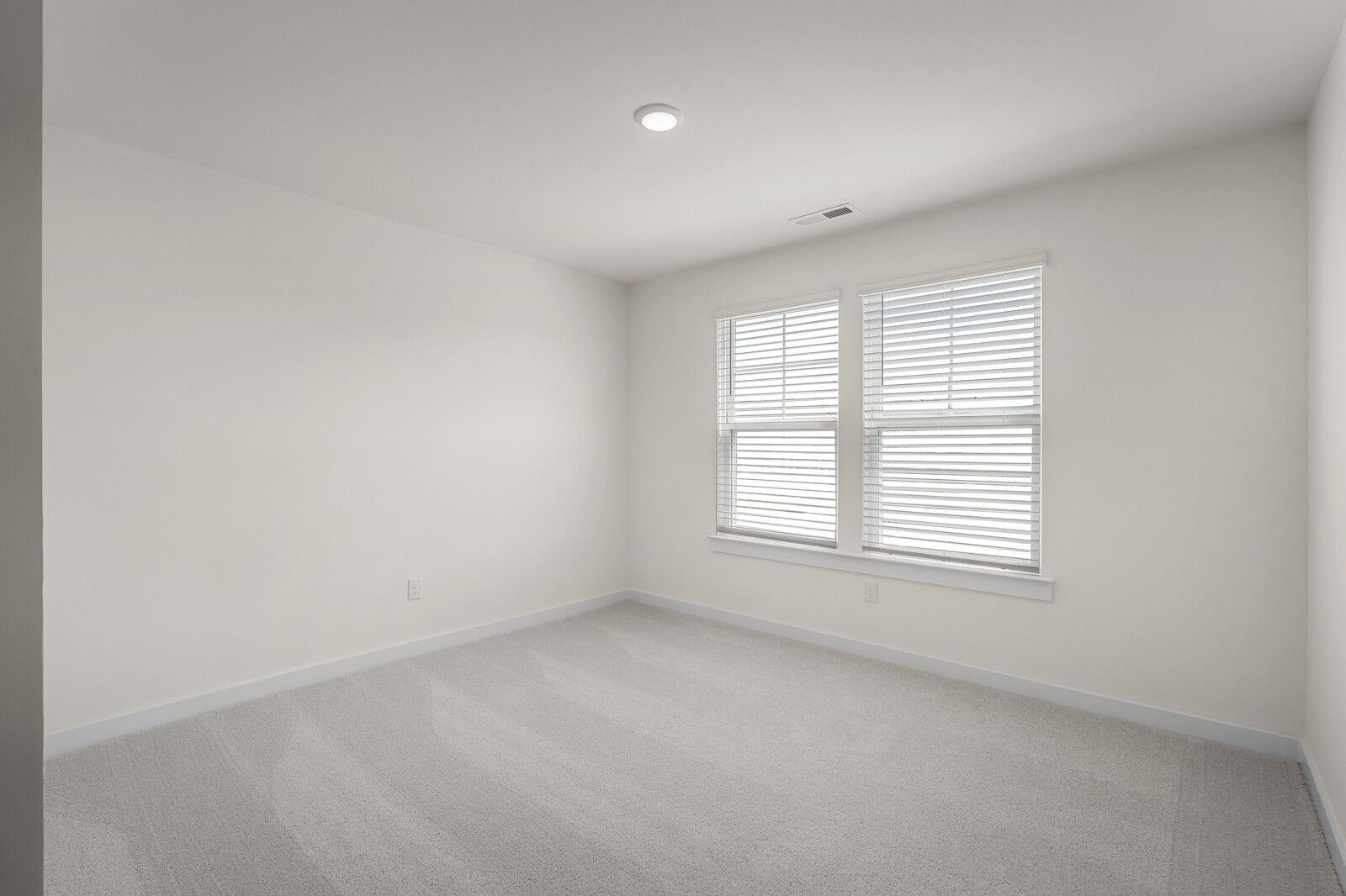 Spacious, carpeted bedroom with neutral walls and windows in The Willow floor plan at Woods Crossing, Gallatin, Tennessee.