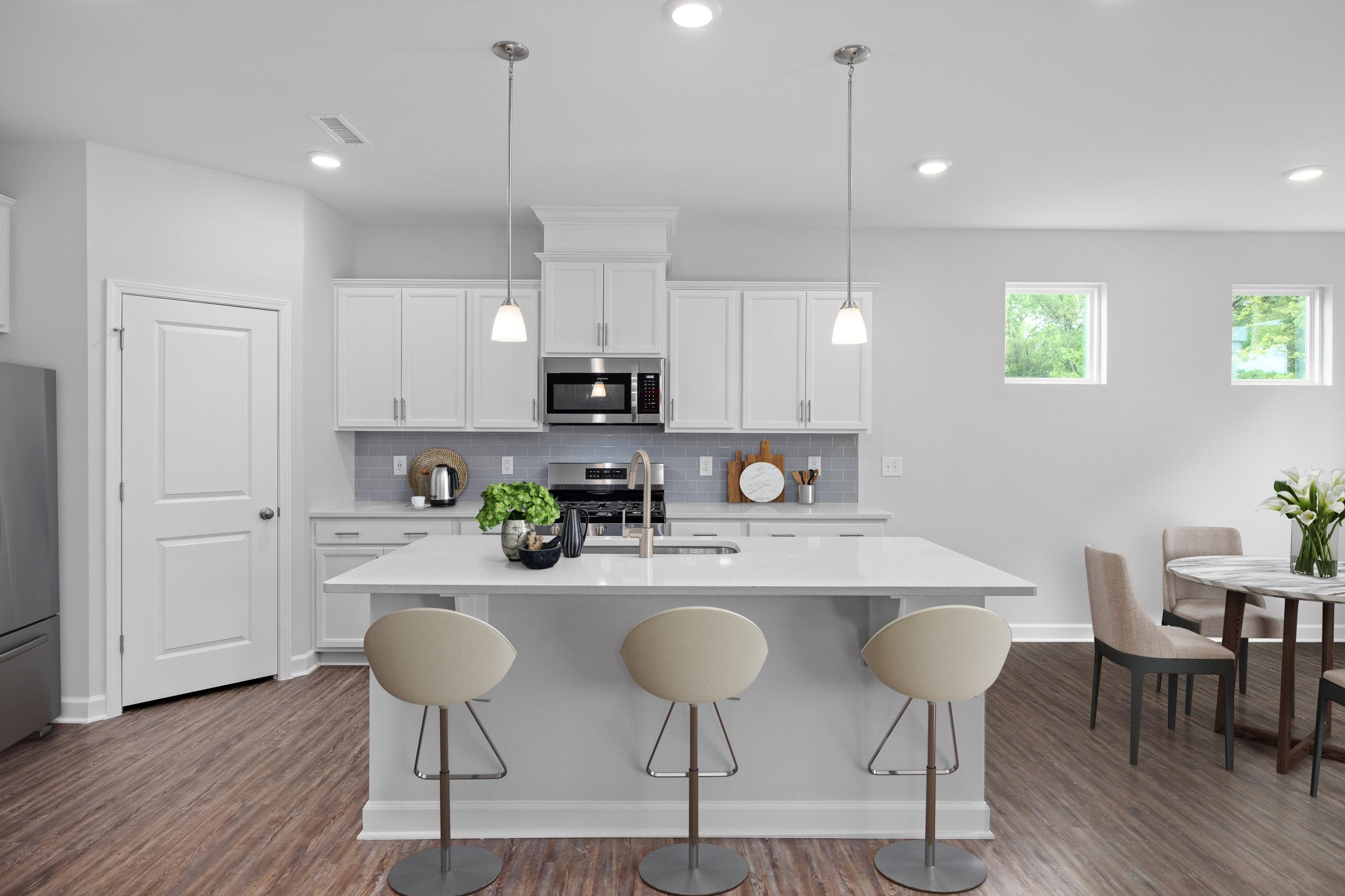 Modern open-concept kitchen dining at Gregory Village Townhomes in Lillington NC with white island, bar stools, hardwood floors