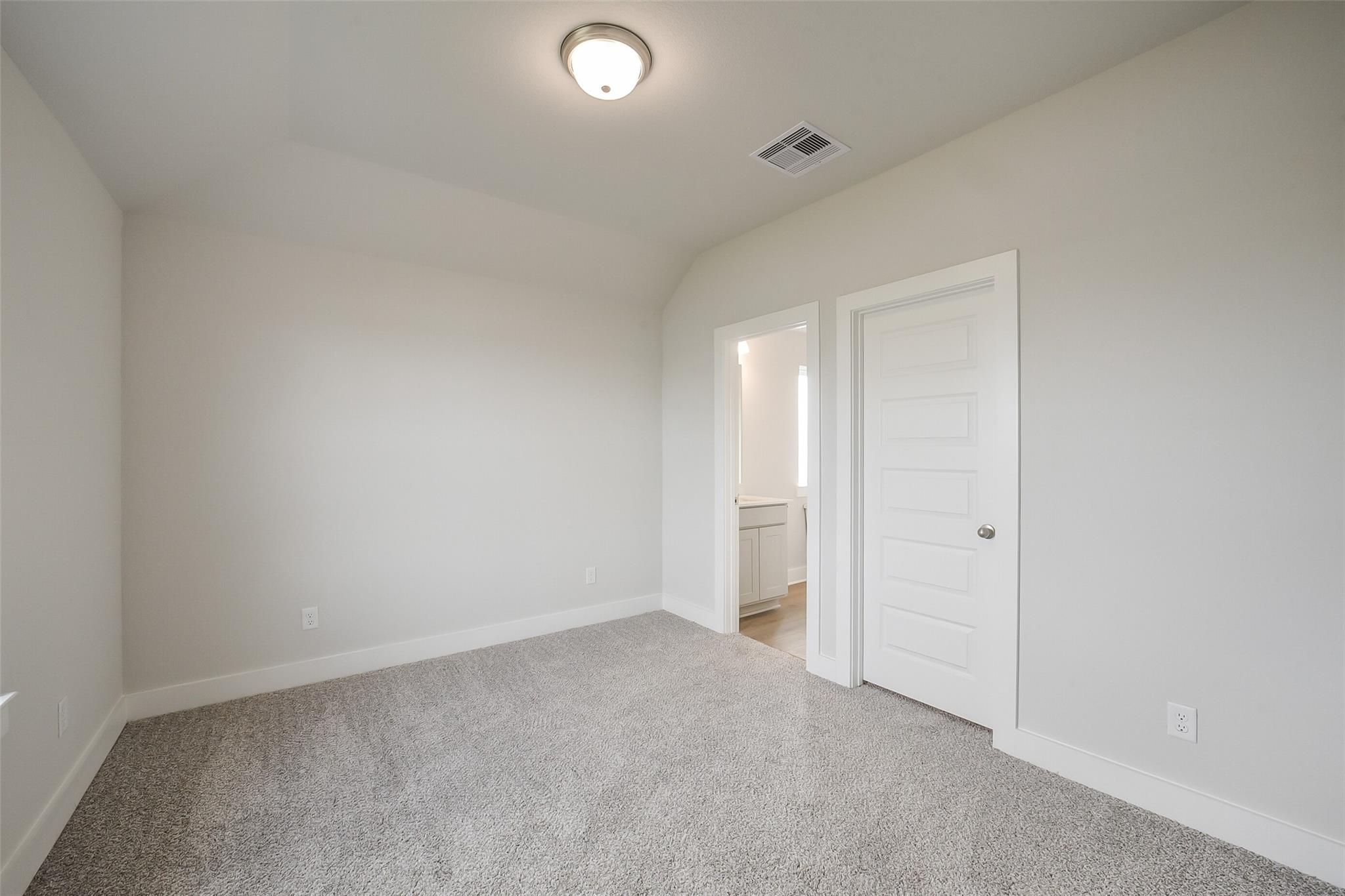 Bright bedroom with attached bath vanity, carpet flooring, and white doors in Davidson Homes Philip B, Rosharon Texas