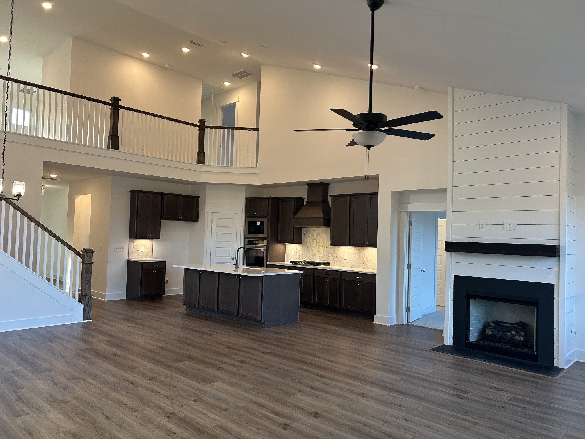Two-story open-concept living area with modern kitchen island, black fireplace, and upstairs balcony in Davidson Homes Ridgeport F, Mt. Juliet