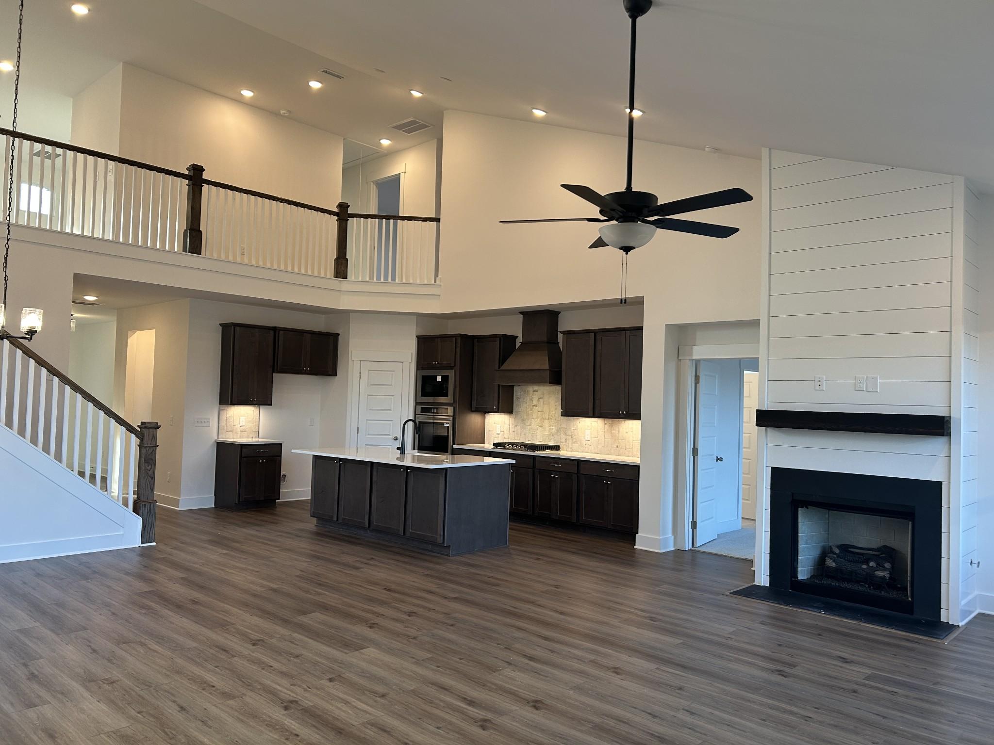 Two-story open-concept living area with modern kitchen island, black fireplace, and upstairs balcony in Davidson Homes Ridgeport F, Mt. Juliet