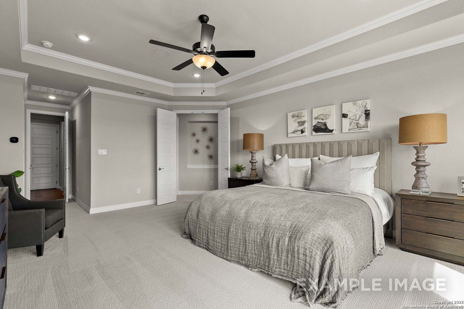 Luxurious master bedroom with king bed, ceiling fan, and en-suite door in Davidson Homes The Summerlin B, Castroville, Texas