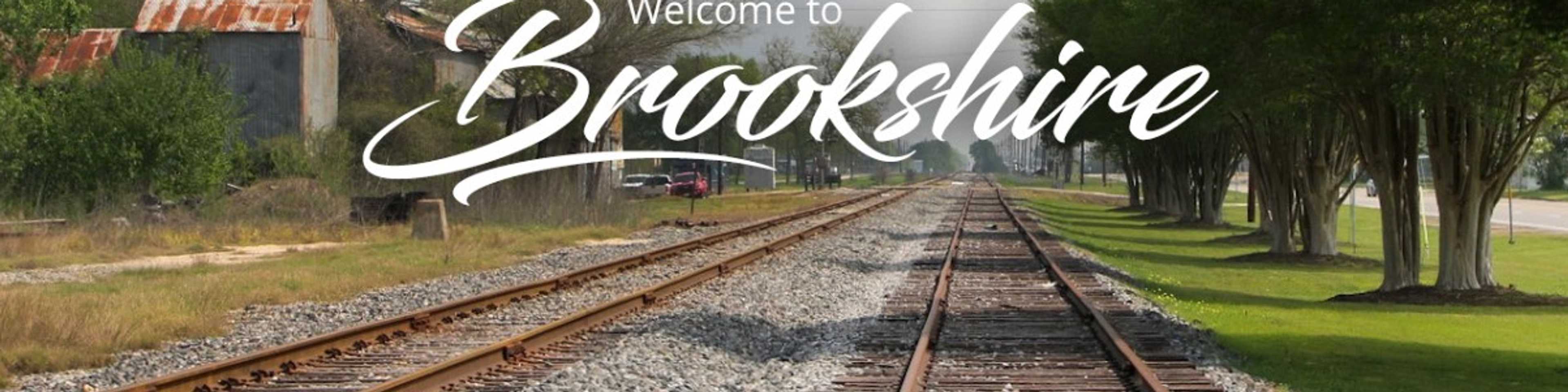Welcome to Brookshire: Scenic railroad tracks lined with trees and rustic red-roof barn