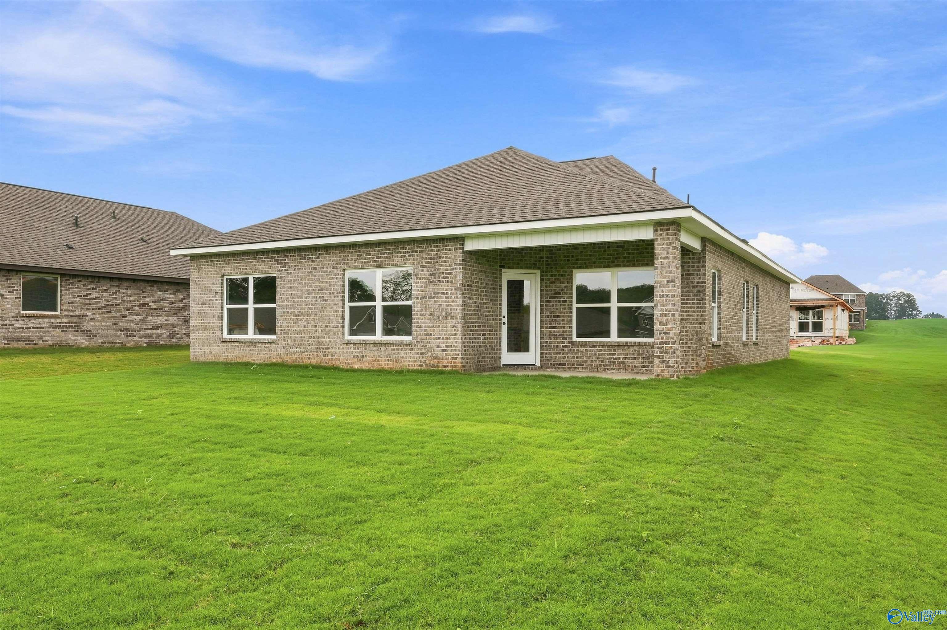 Rear exterior of brick 3-bedroom Davidson Homes Franklin C plan with covered patio and large fenced yard in The Meadows, Athens, Alabama