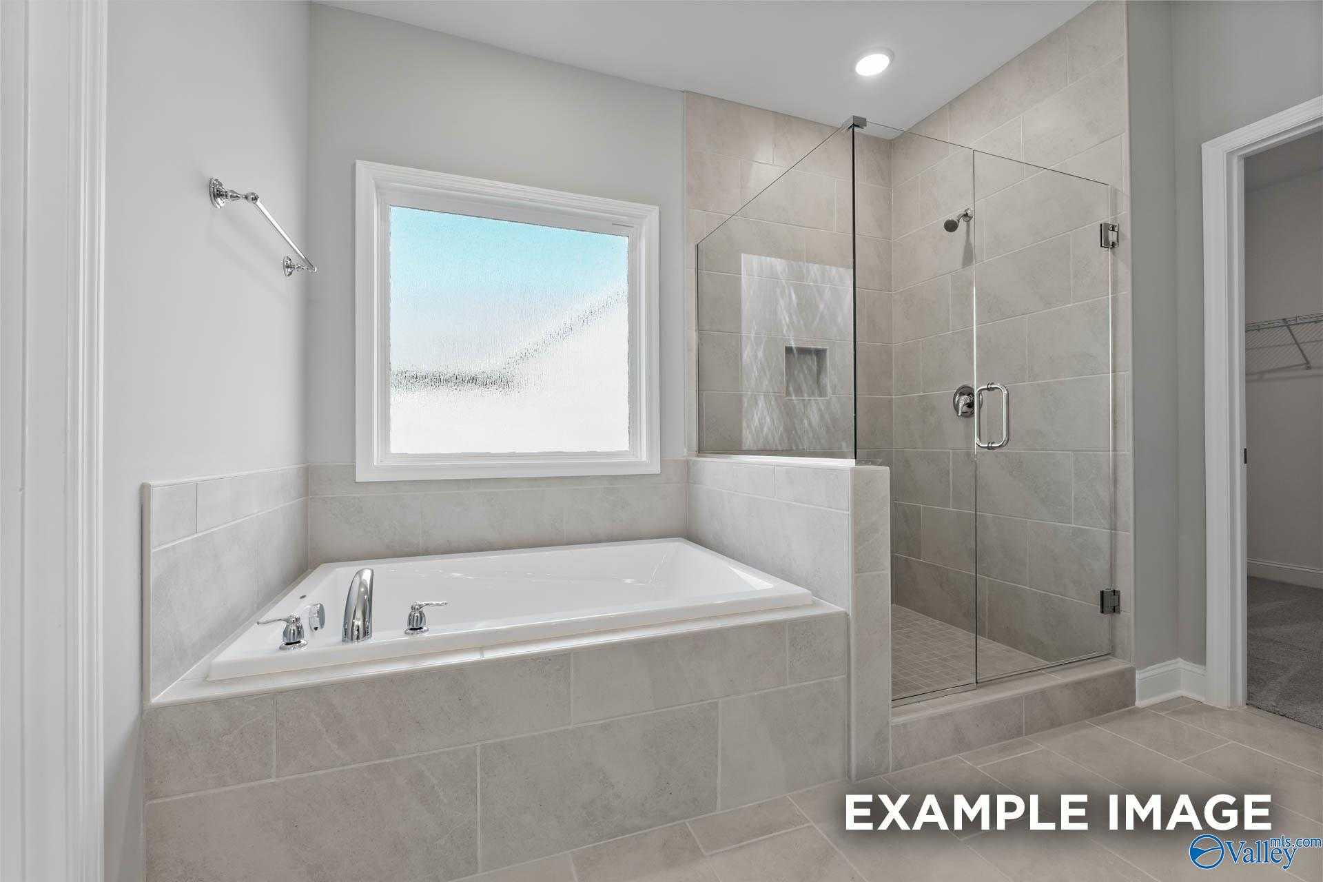 Modern master bathroom featuring freestanding tub, glass walk-in shower, and large window in Davidson Homes The Rockford D, Hazel Green, AL