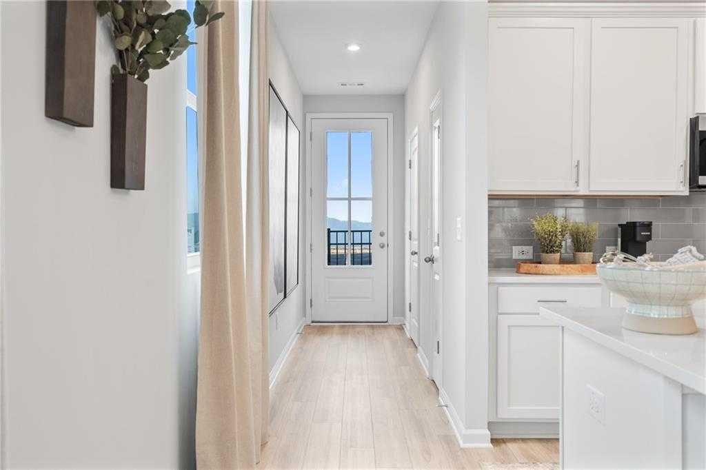Bright hallway with white kitchen cabinets, subway tile backsplash, and glass door to backyard in Wilmington B home, Emerson, GA