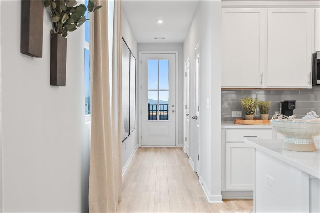 Bright hallway with hardwood floors, white shaker cabinets, subway tile backsplash, and glass door to scenic mountain view in Davidson Homes Wilmington B, Emerson, GA