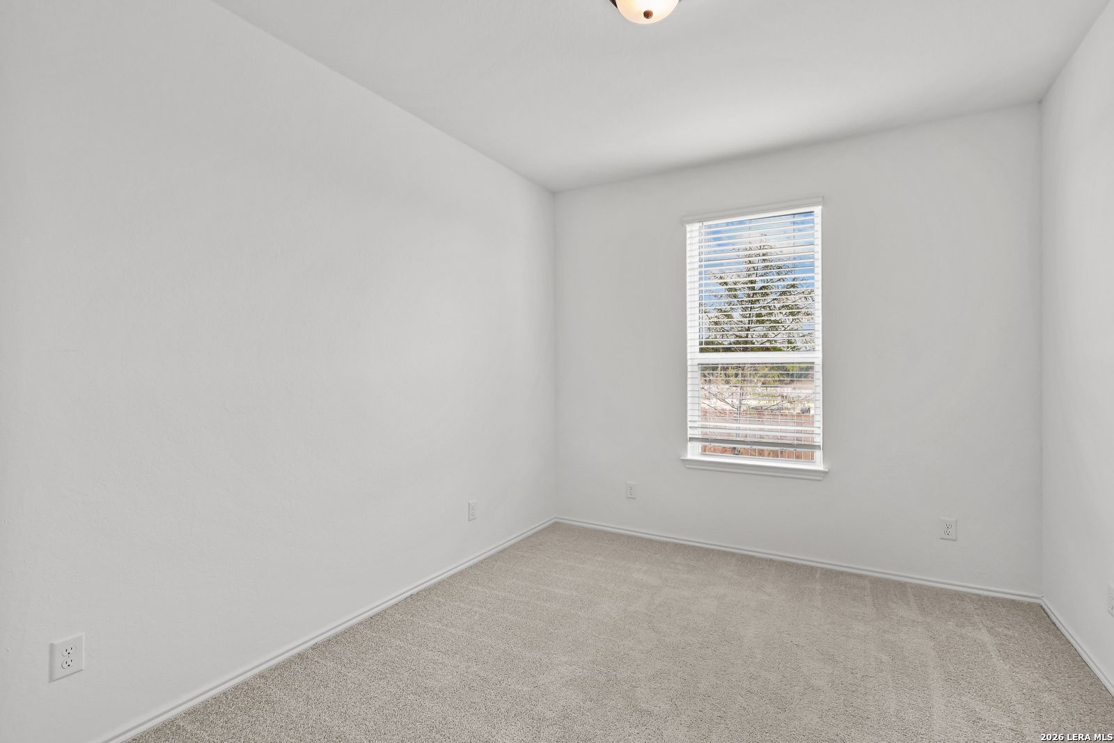 Bright, carpeted bedroom with white walls and a large window in The Gillian C floor plan at Meadows at Oak Creek, TX.