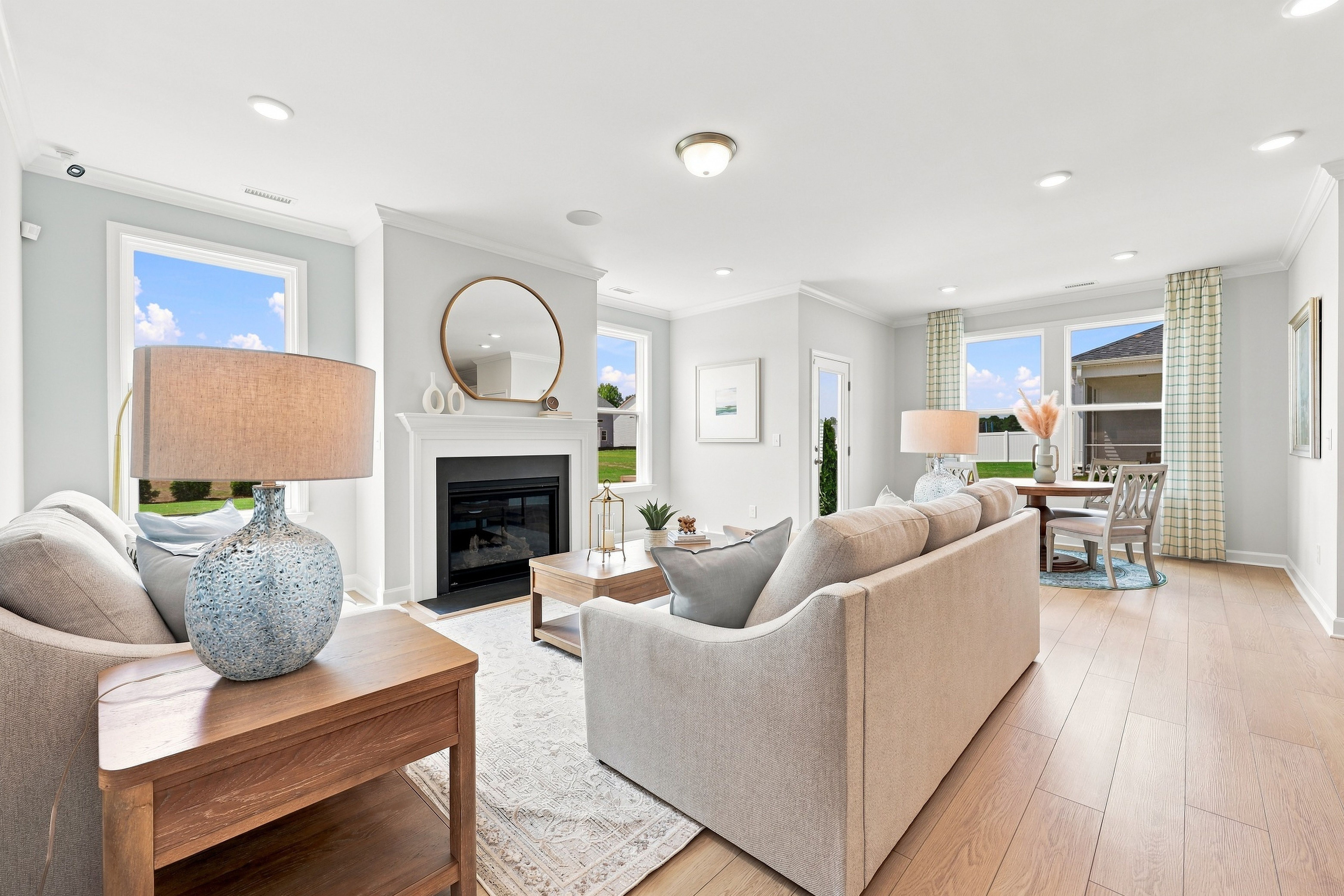 Open-concept living room in The Daphne D featuring a fireplace, modern decor, and bright dining area by Davidson Homes.