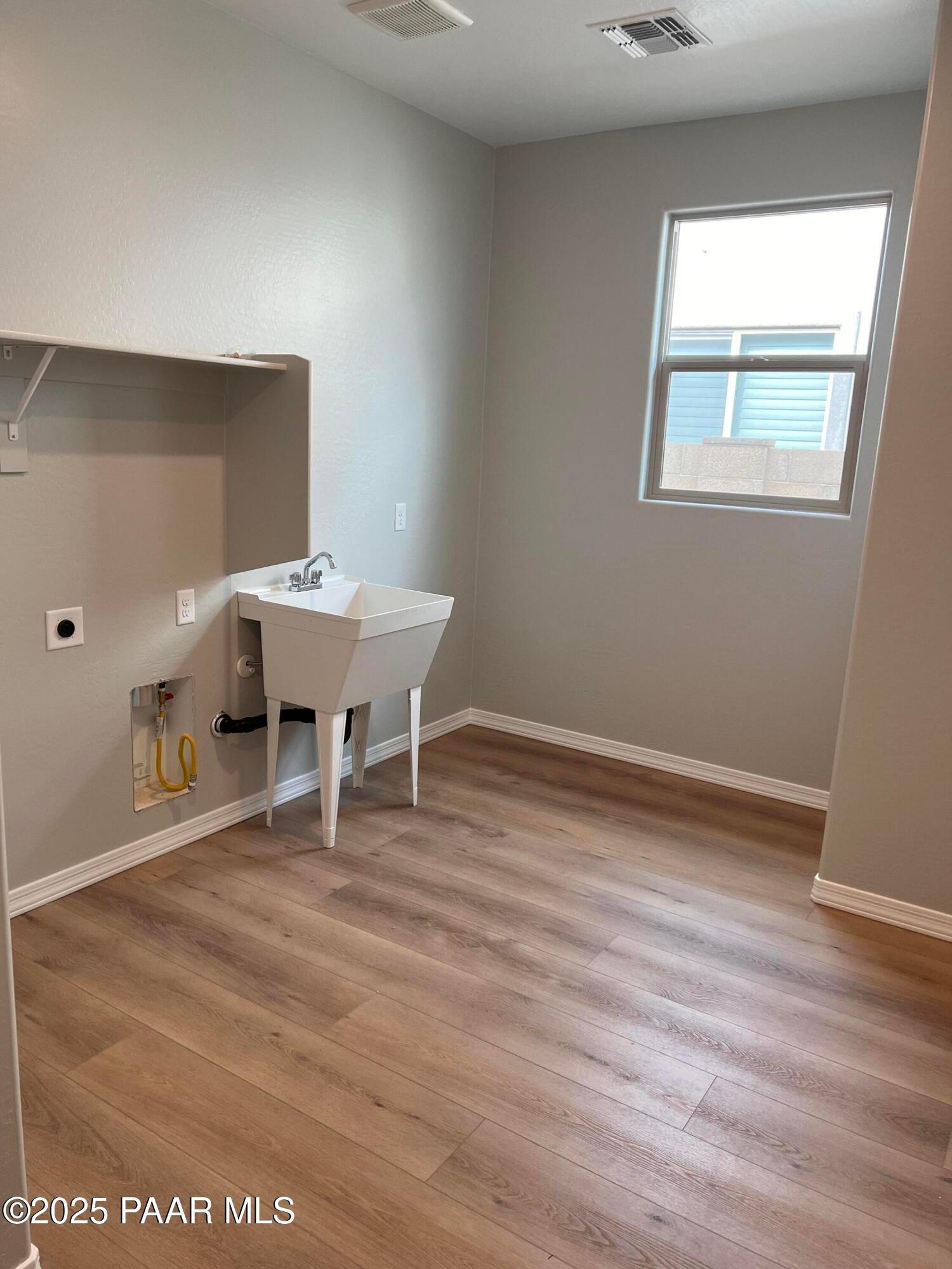 Spacious laundry room with white utility sink, washer dryer hookups, and laminate flooring in Davidson Homes The Inspiration B, Prescott Valley, Arizona