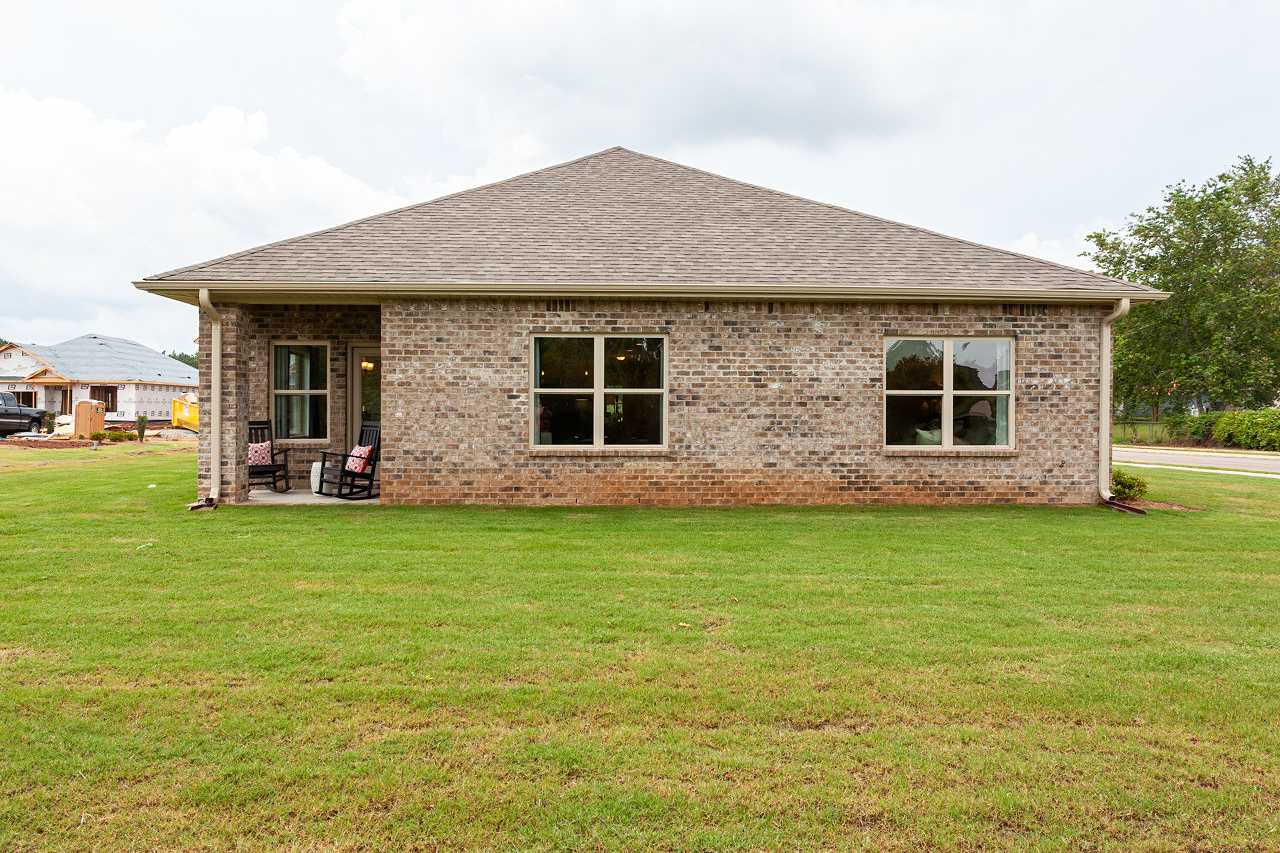 Brick home side exterior at Williams Pointe in Huntsville Alabama with covered porch, rocking chairs, and lush green lawn