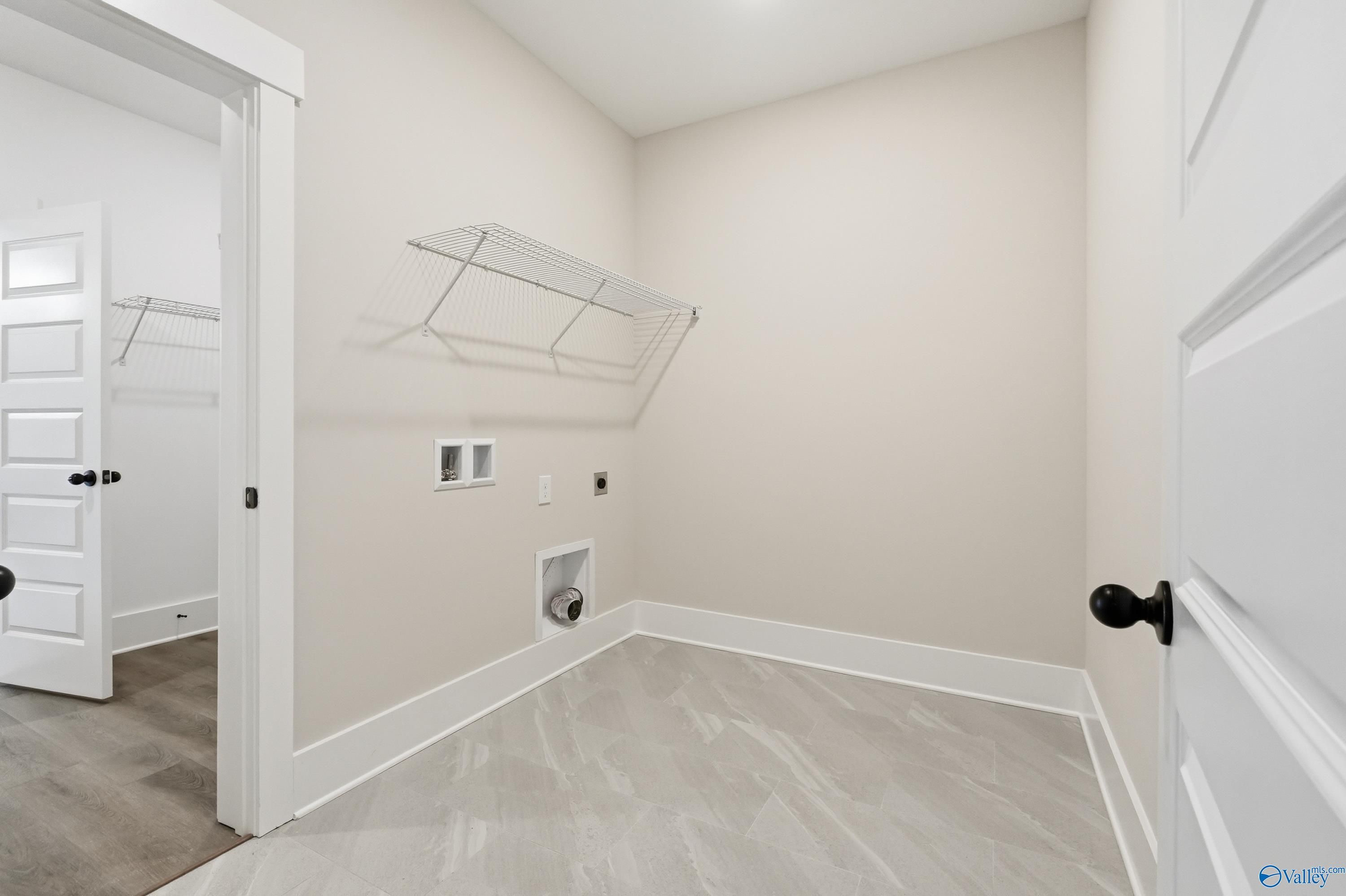 Spacious laundry room with wire shelving, washer/dryer hookups, and luxury vinyl plank flooring in Davidson Homes The Finleigh, Meridianville, Alabama