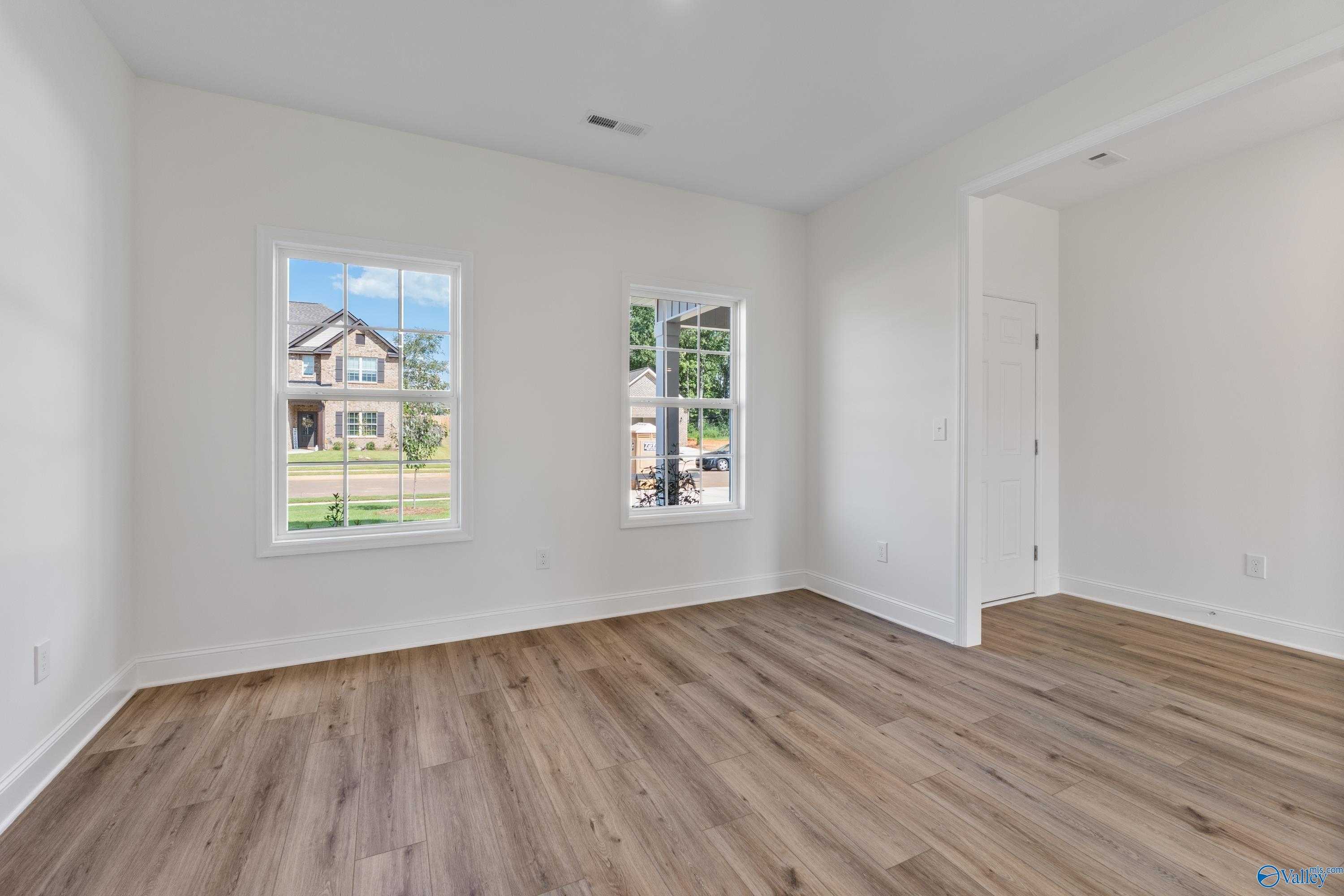 Bright secondary bedroom with hardwood floors and neighborhood view through large windows in Davidson Homes The Shelby A, New Market, AL