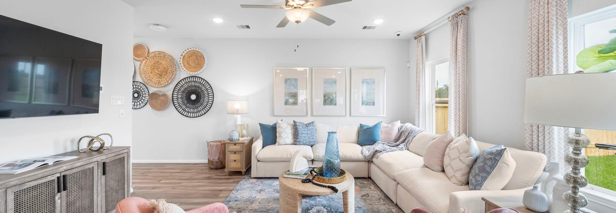 Spacious living room at Hill & Dale Ranch in Splendora TX with beige sectional sofa, pink armchairs, hardwood floors, woven wall art
