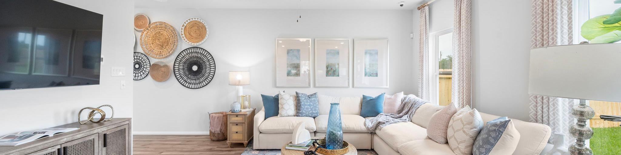 Spacious living room at Hill & Dale Ranch in Splendora TX with beige sectional sofa, pink armchairs, hardwood floors, woven wall art