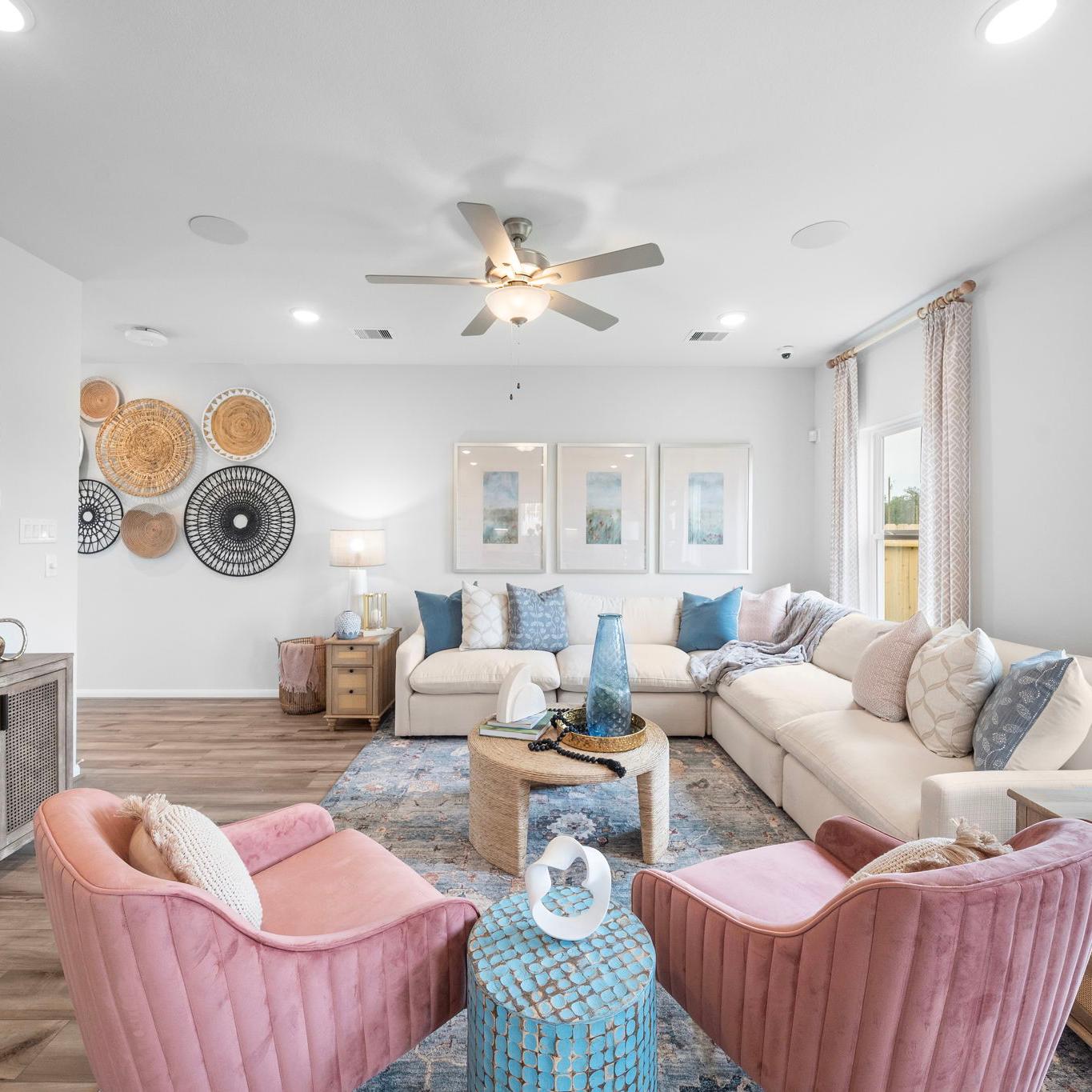 Spacious living room at Hill & Dale Ranch in Splendora TX with beige sectional sofa, pink armchairs, hardwood floors, woven wall art