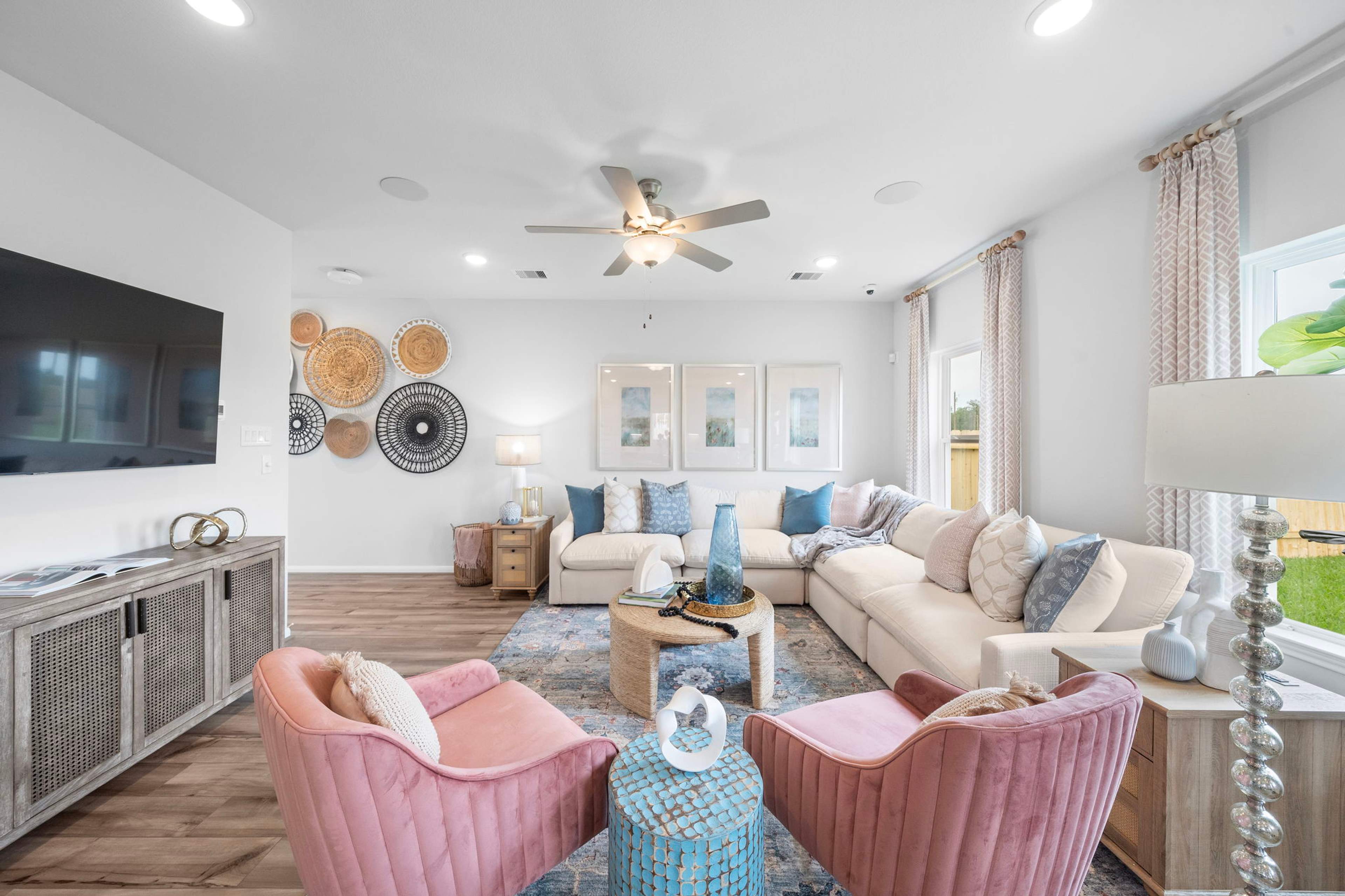 Spacious living room at Hill & Dale Ranch in Splendora TX with beige sectional sofa, pink armchairs, hardwood floors, woven wall art