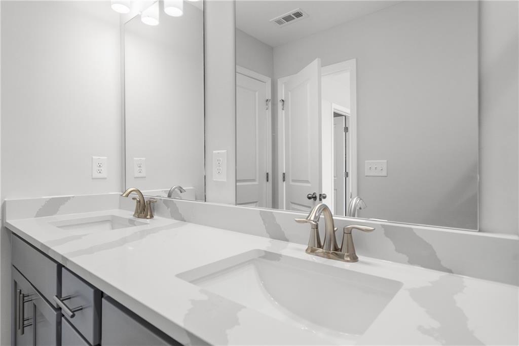 Modern double vanity with white quartz countertops, gold faucets, and gray cabinets in The Monroe B master bath, Emerson, Georgia