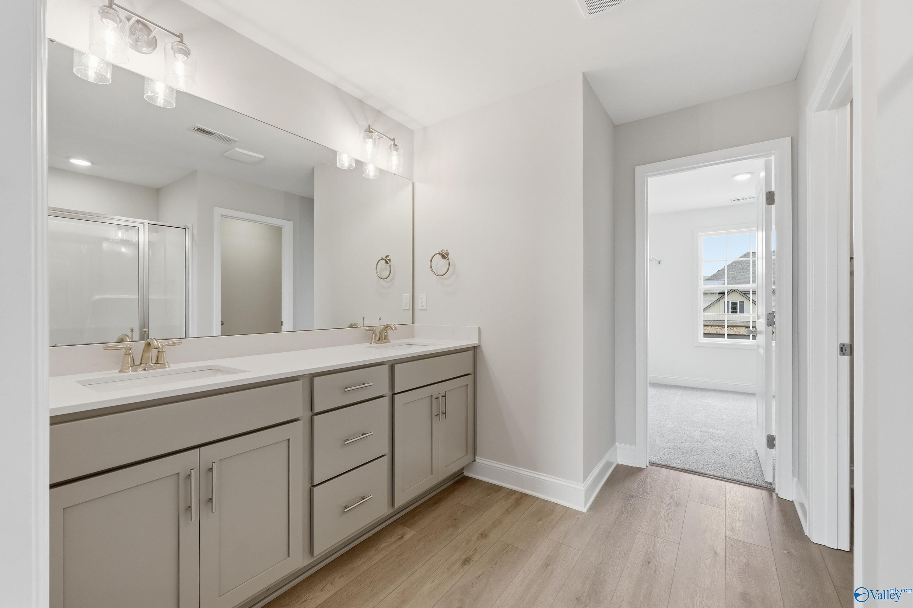 Modern master bath with double gray vanity, large mirror, and glass shower in Davidson Homes The Shelby B, New Market, Alabama