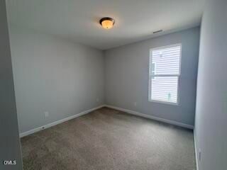 Spacious secondary bedroom with neutral carpet in The Daphne D floor plan at Woodland Crossing in Zebulon, North Carolina.